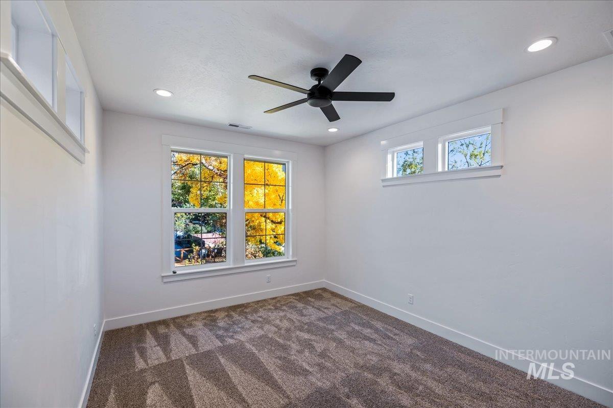 Spare room with dark colored carpet, ceiling fan, and recessed lighting