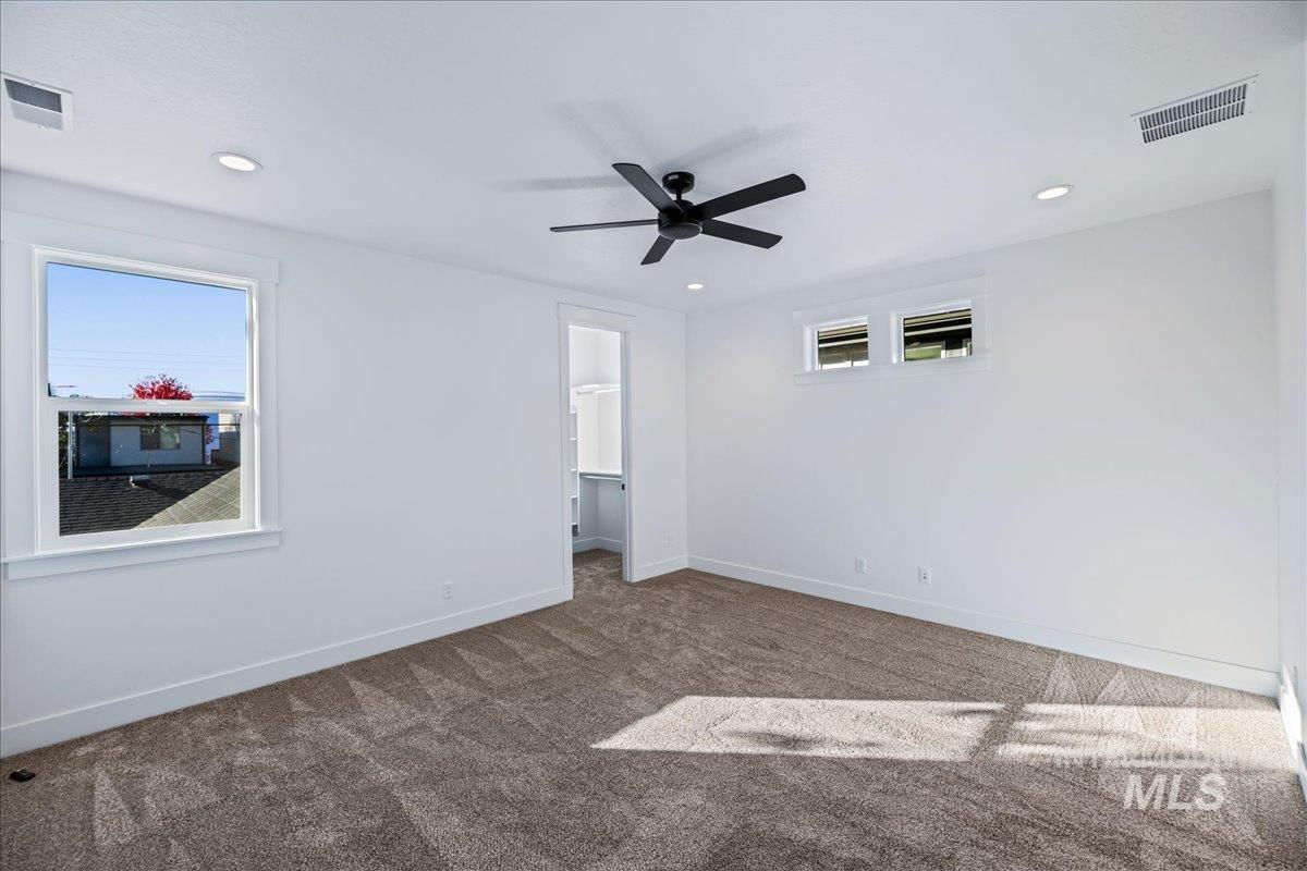 Unfurnished bedroom featuring carpet, a walk in closet, a ceiling fan, and recessed lighting