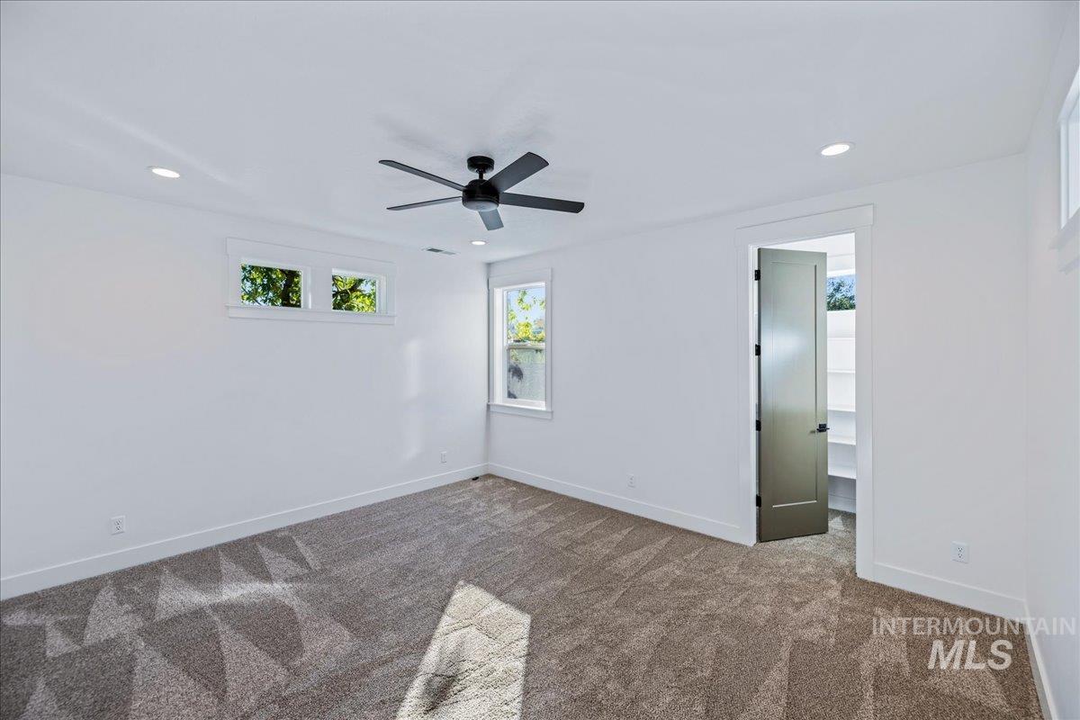 Unfurnished bedroom featuring a spacious closet, carpet floors, recessed lighting, and ceiling fan