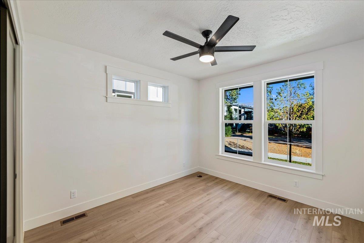 Spare room featuring light wood-style flooring, a textured ceiling, and a ceiling fan