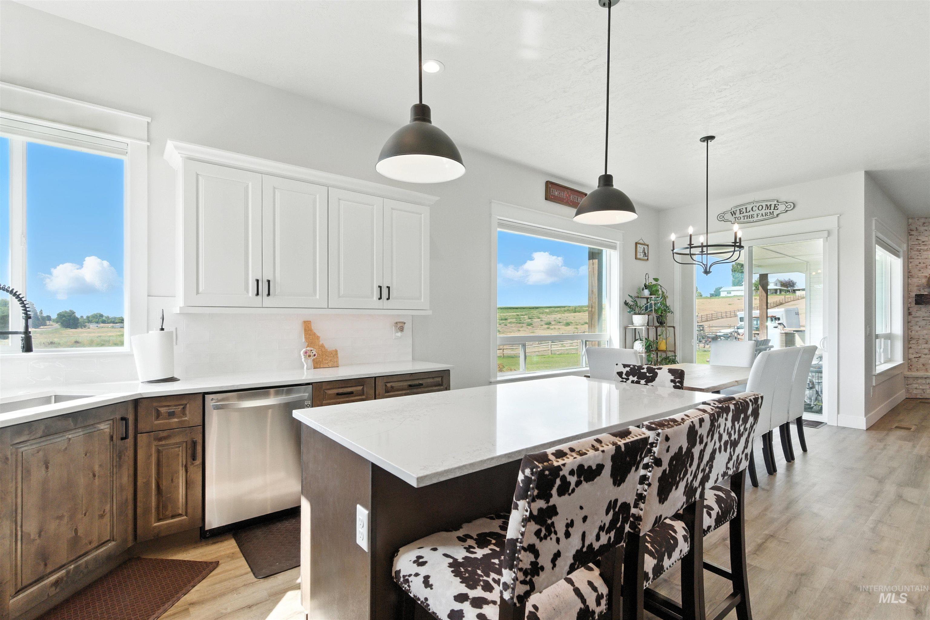 Kitchen with dishwasher, light wood-style flooring, a breakfast bar, light countertops, and a chandelier
