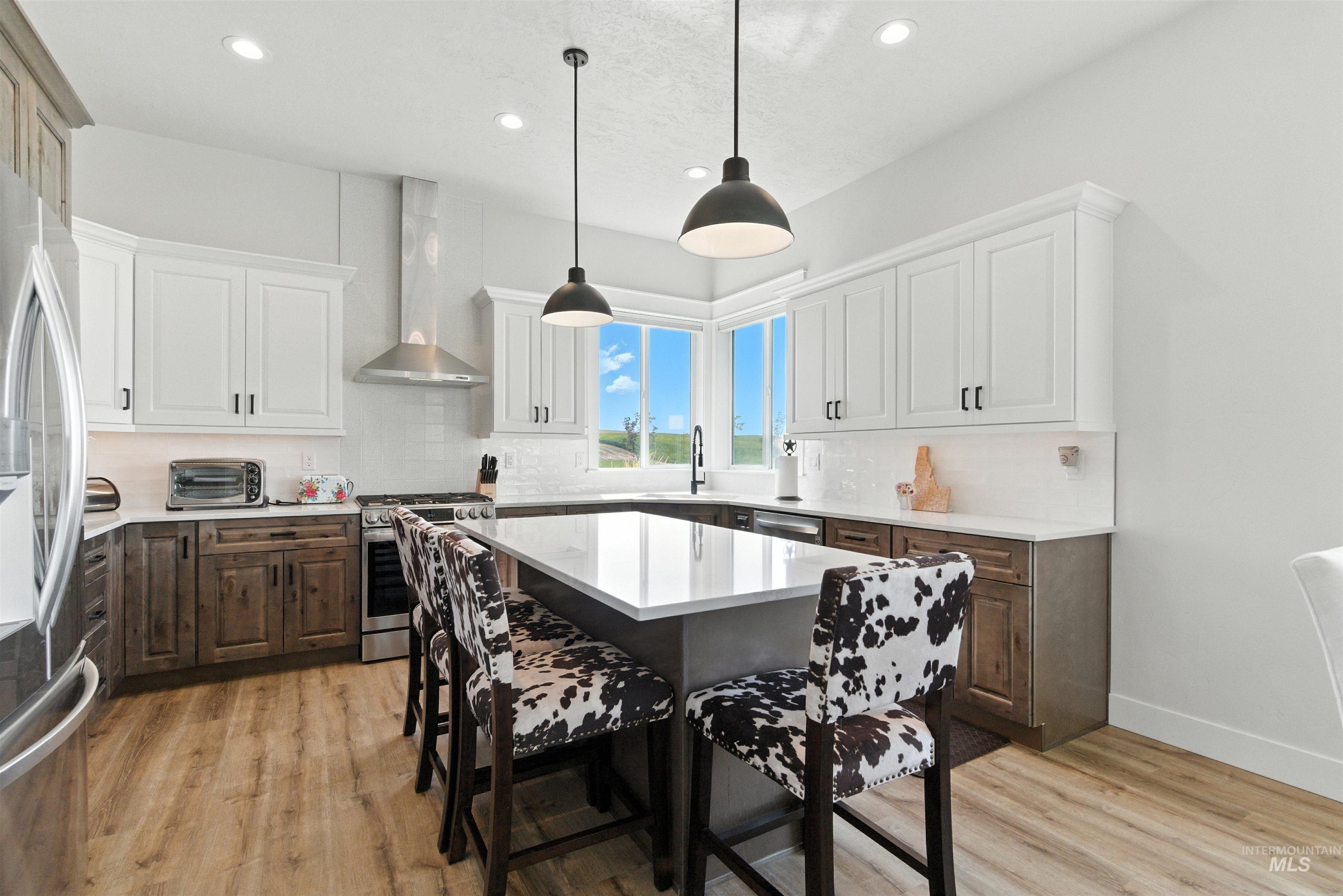 Kitchen featuring tasteful backsplash, a center island, light wood-type flooring, light countertops, and a breakfast bar