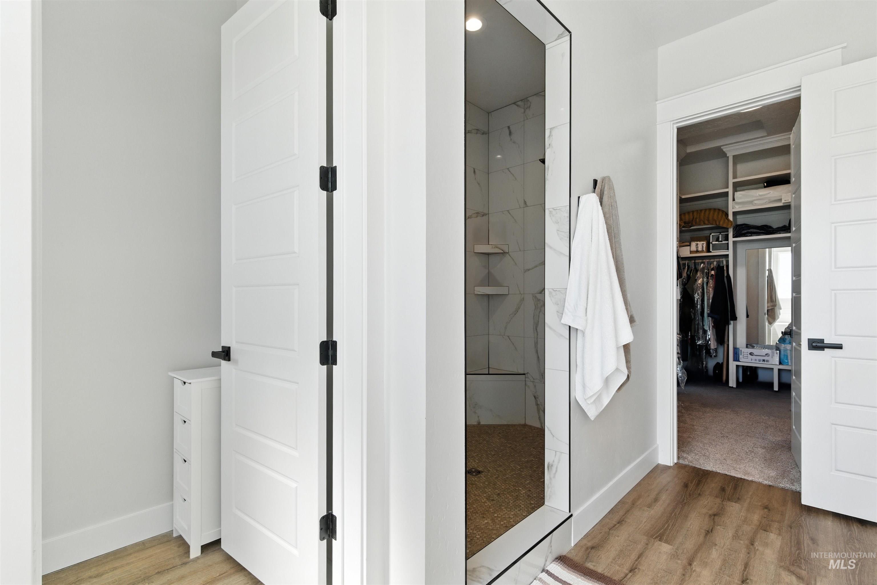 Full bathroom featuring wood finished floors, walk in shower, a spacious closet, and recessed lighting