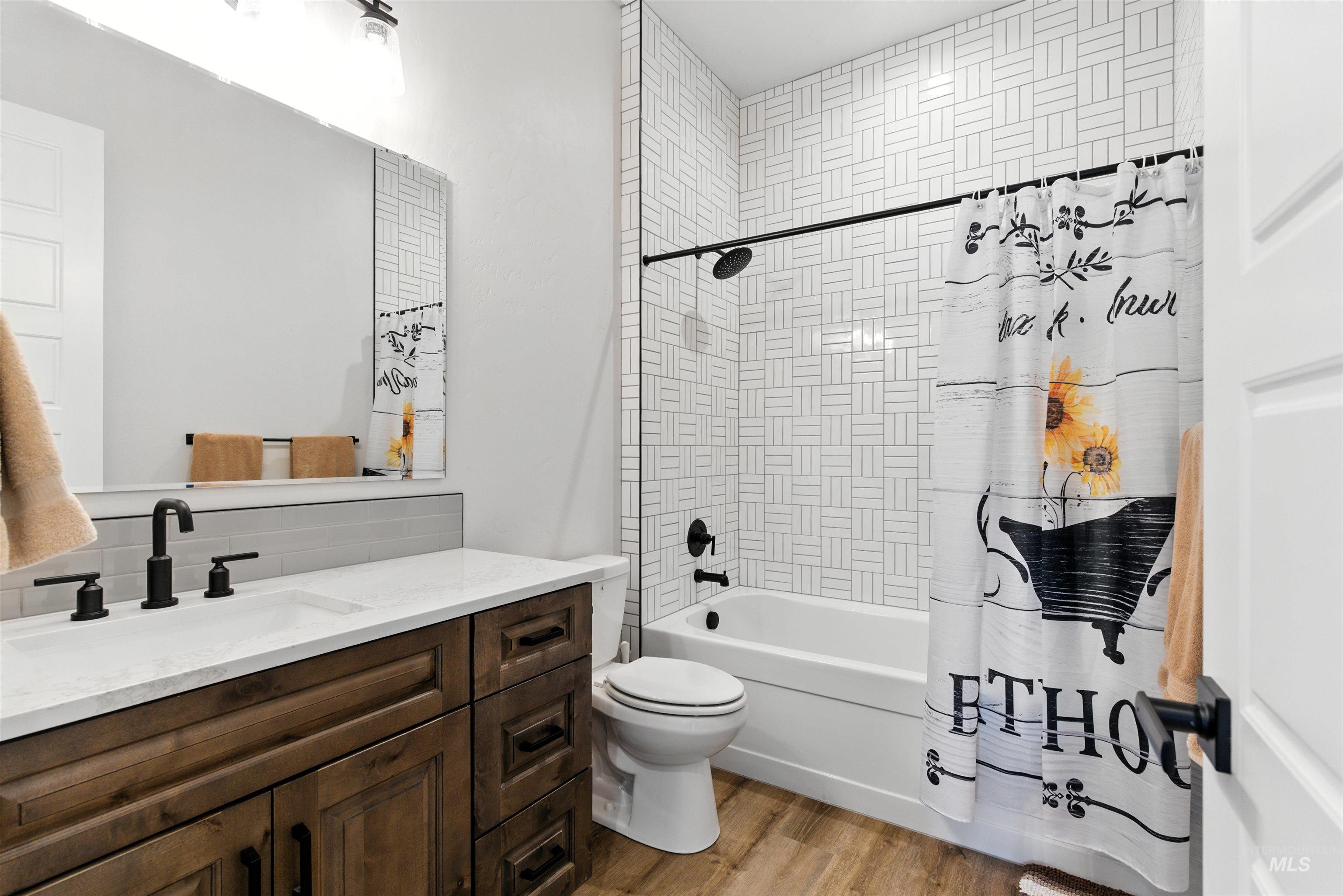 Bathroom featuring vanity, wood finished floors, and shower / tub combo