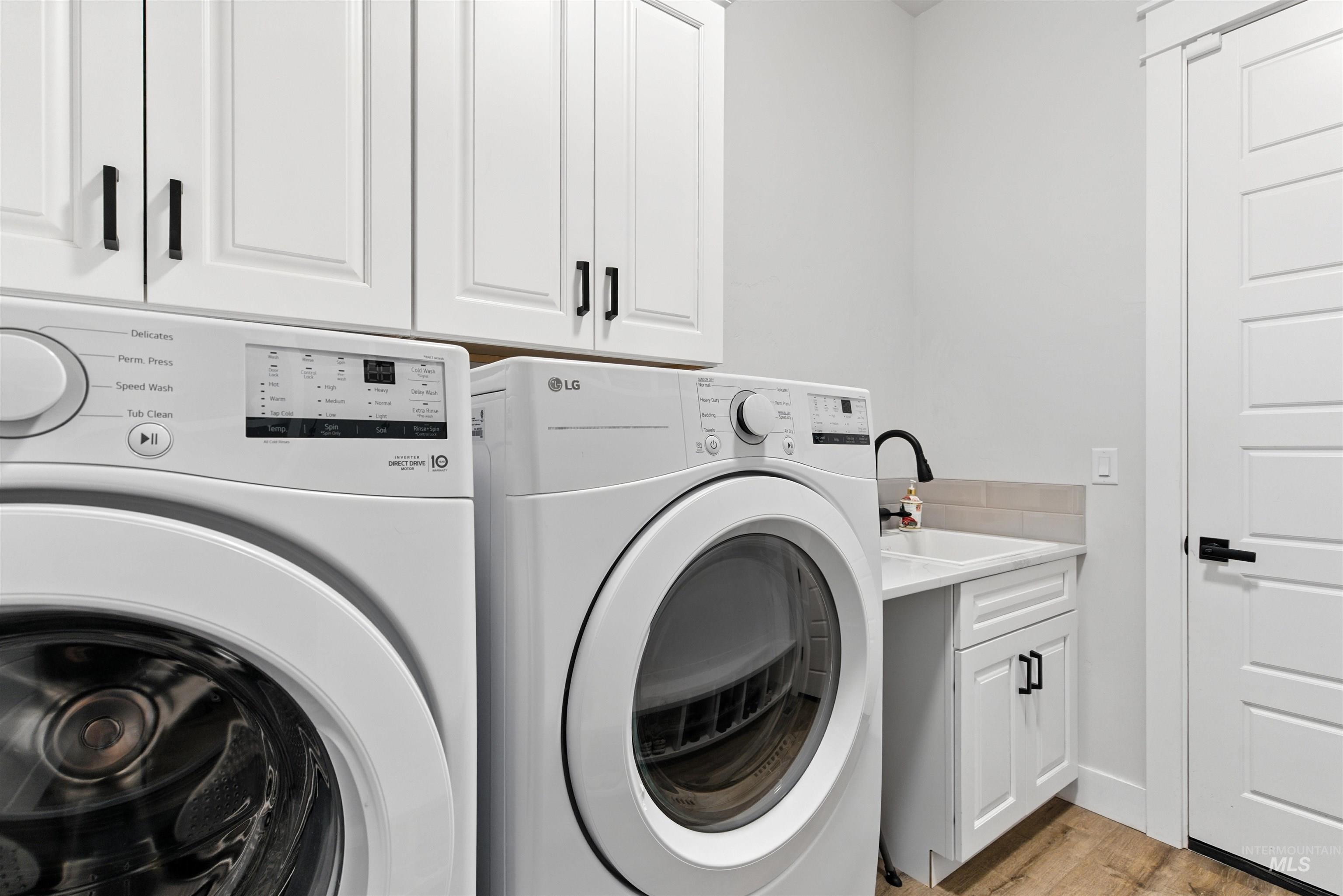 Laundry room with cabinet space, washing machine and clothes dryer, and light wood-style flooring