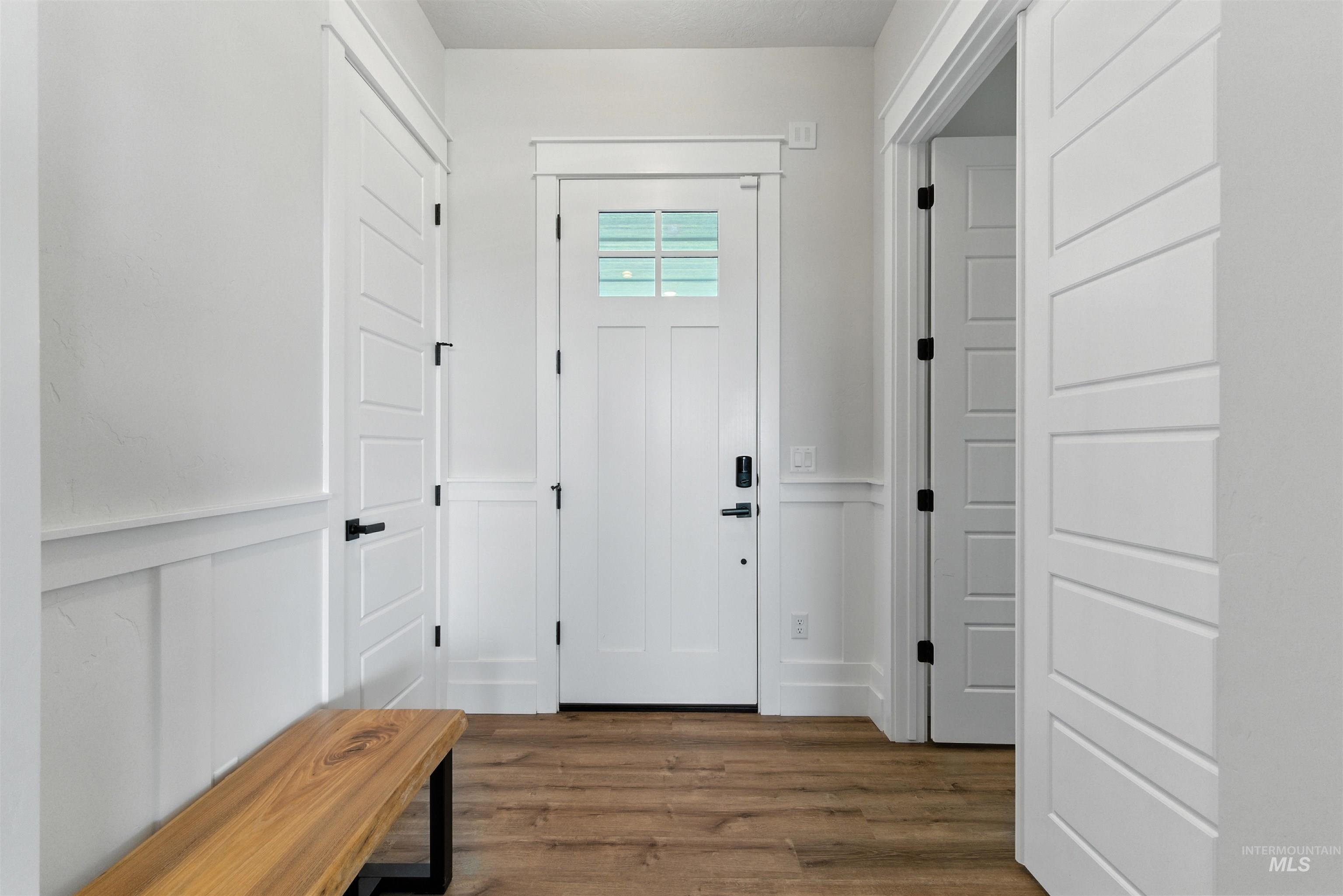 Entrance foyer with wainscoting, wood finished floors, and a decorative wall