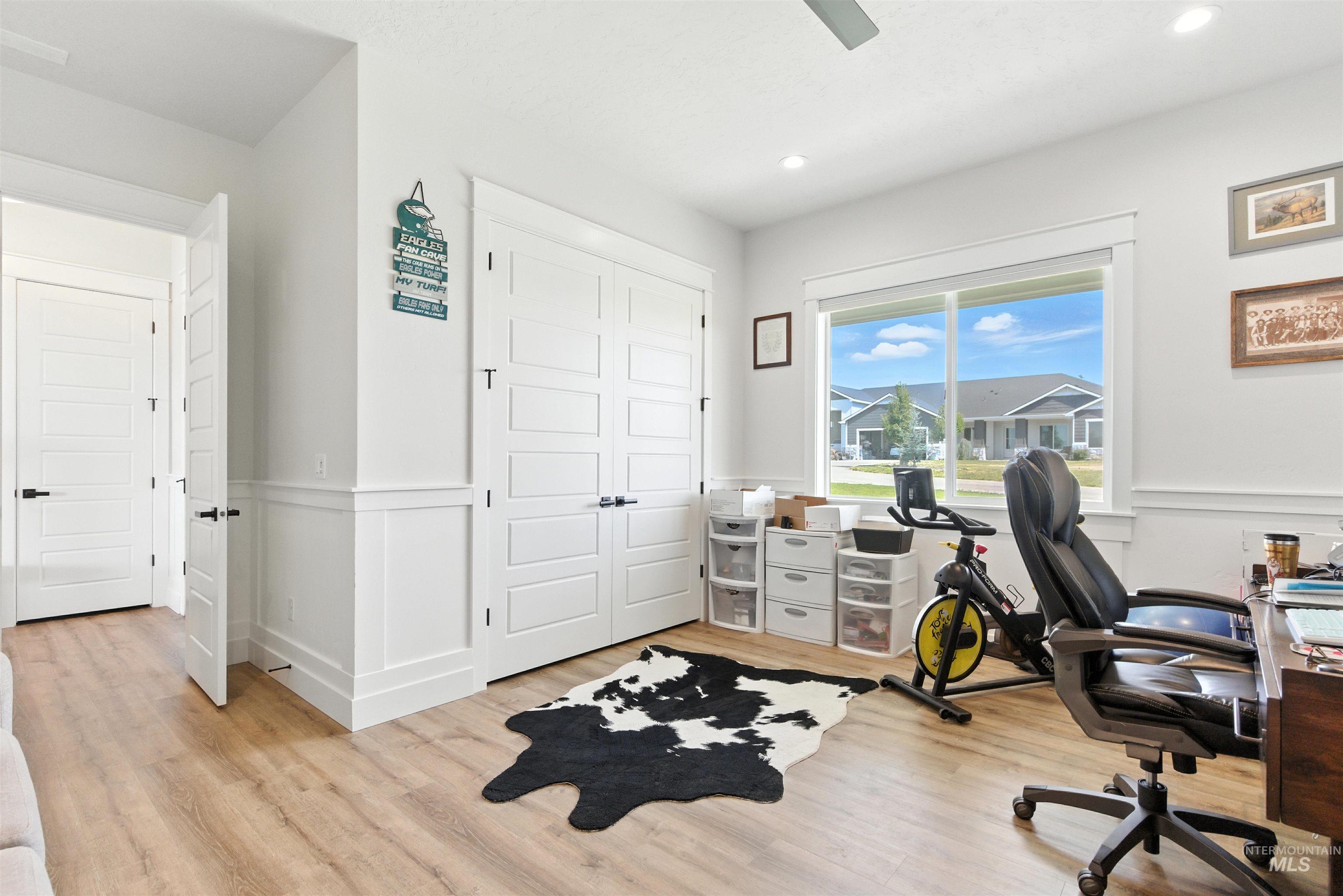 Office space featuring wainscoting, a decorative wall, light wood-style flooring, and recessed lighting