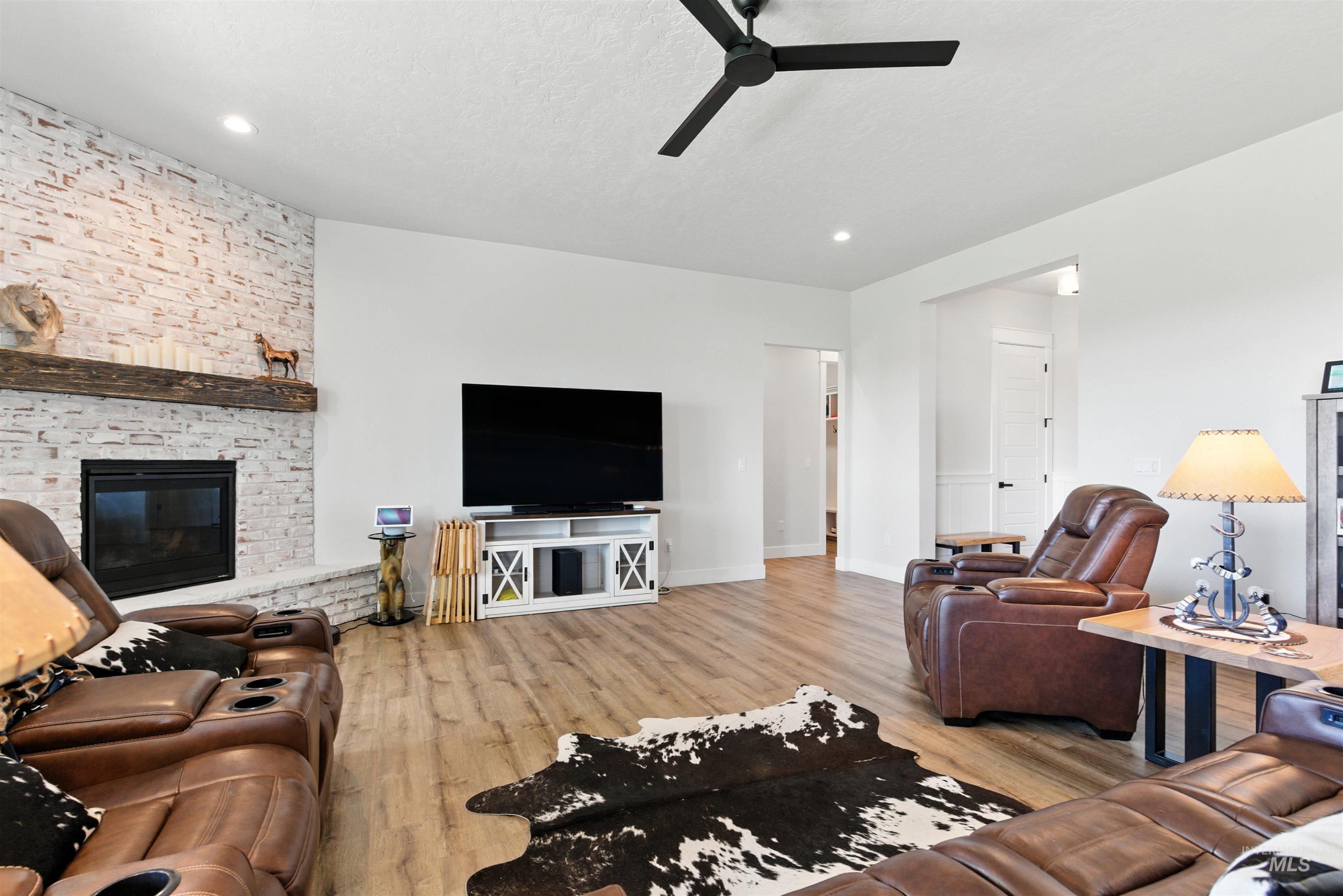 Living area with wood finished floors, a fireplace, ceiling fan, and recessed lighting