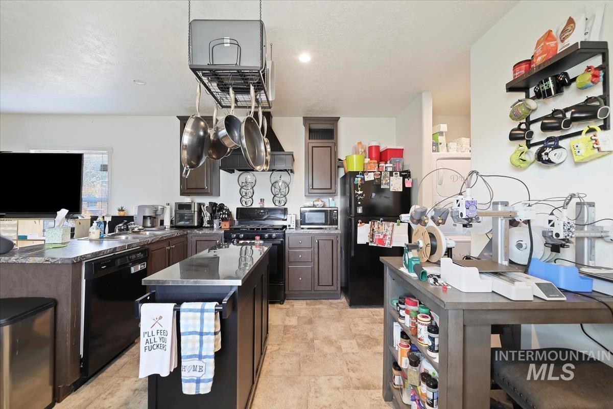 Kitchen with black appliances, dark countertops, dark brown cabinets, a peninsula, and a kitchen island