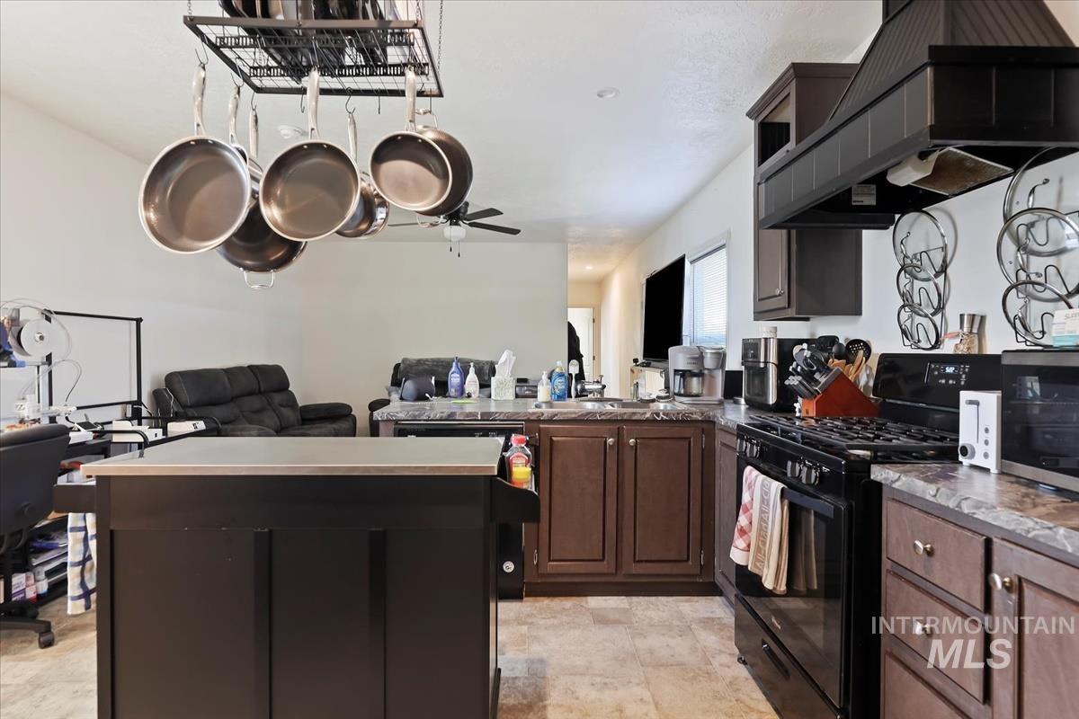 Kitchen with open floor plan, extractor fan, black range with gas cooktop, and a kitchen island