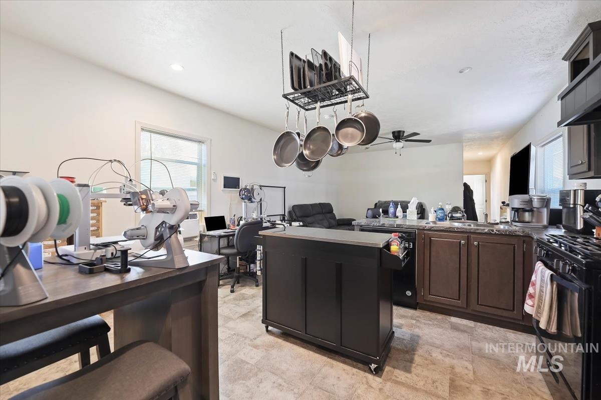 Kitchen with black appliances, open floor plan, a peninsula, a kitchen island, and a ceiling fan