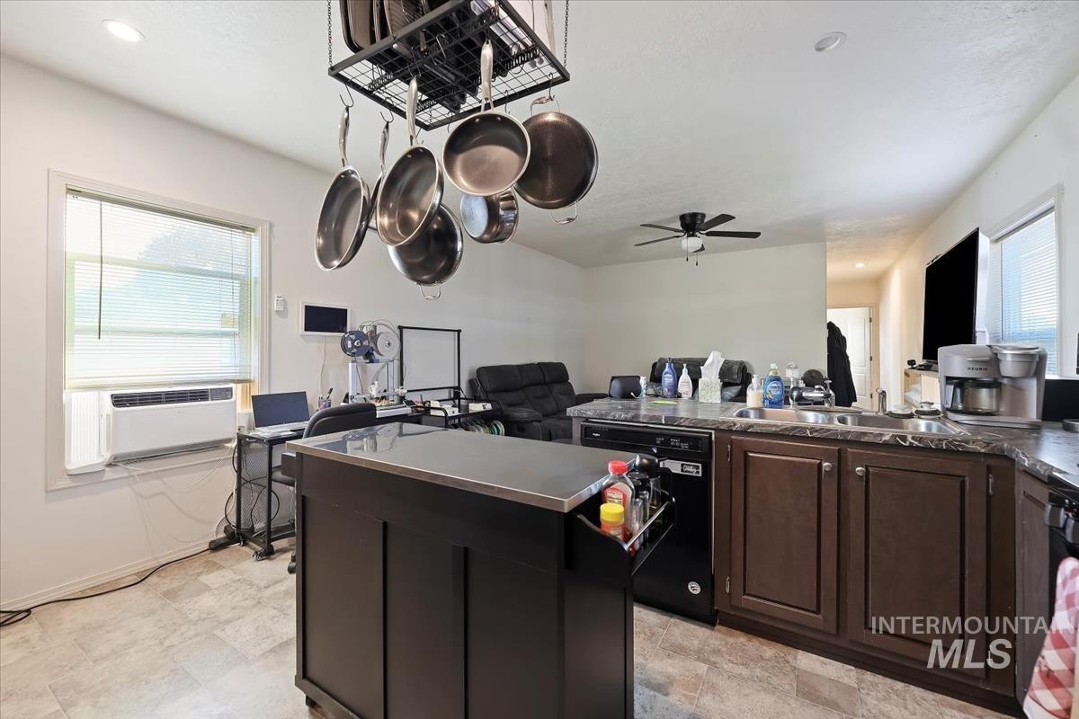 Kitchen featuring dark countertops, open floor plan, dishwasher, a ceiling fan, and a center island