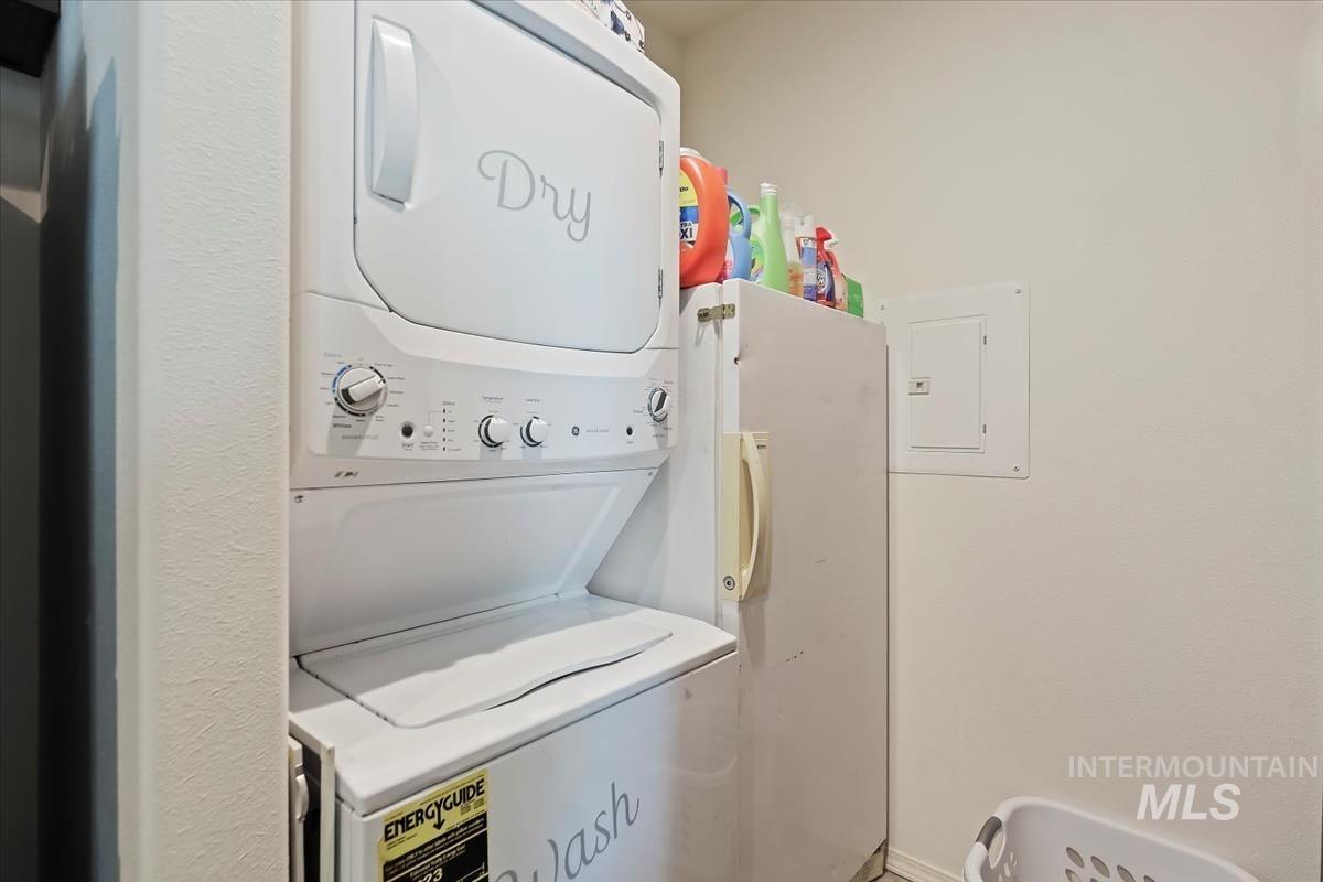 Laundry room featuring electric panel and estacked washer and dryer