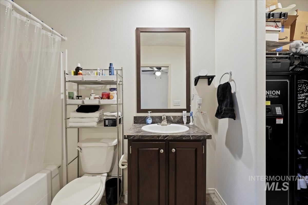 Bathroom with vanity, shower / bath combo with shower curtain, and a ceiling fan