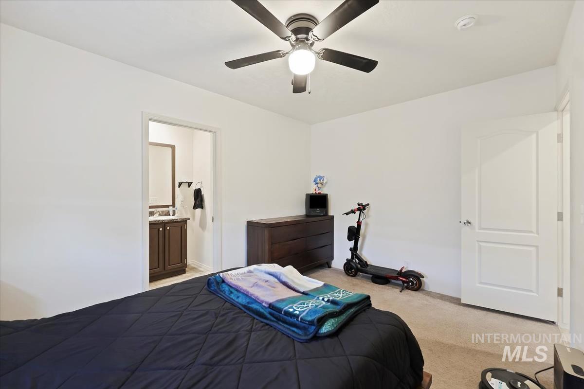 Bedroom with light carpet, ensuite bath, and ceiling fan