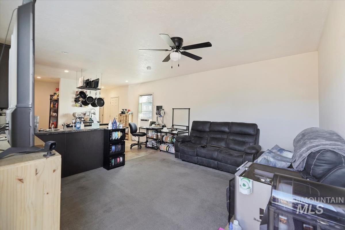 Living area featuring a ceiling fan and carpet flooring