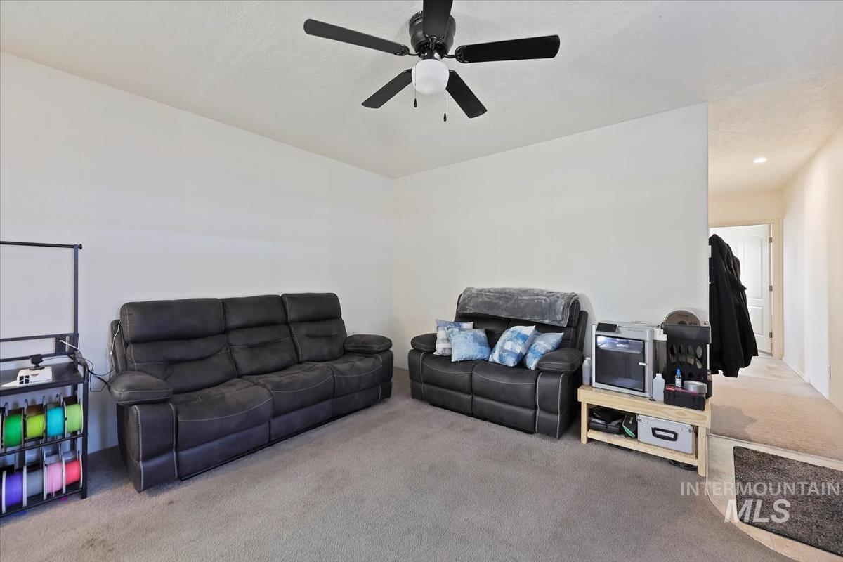 Living room featuring carpet flooring and a ceiling fan
