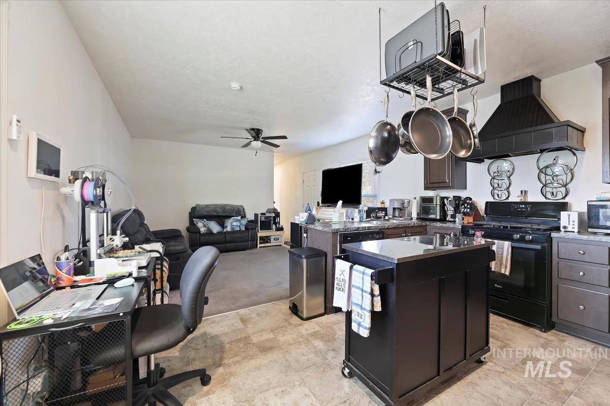 Kitchen with black gas stove, custom range hood, a center island, a peninsula, and open floor plan