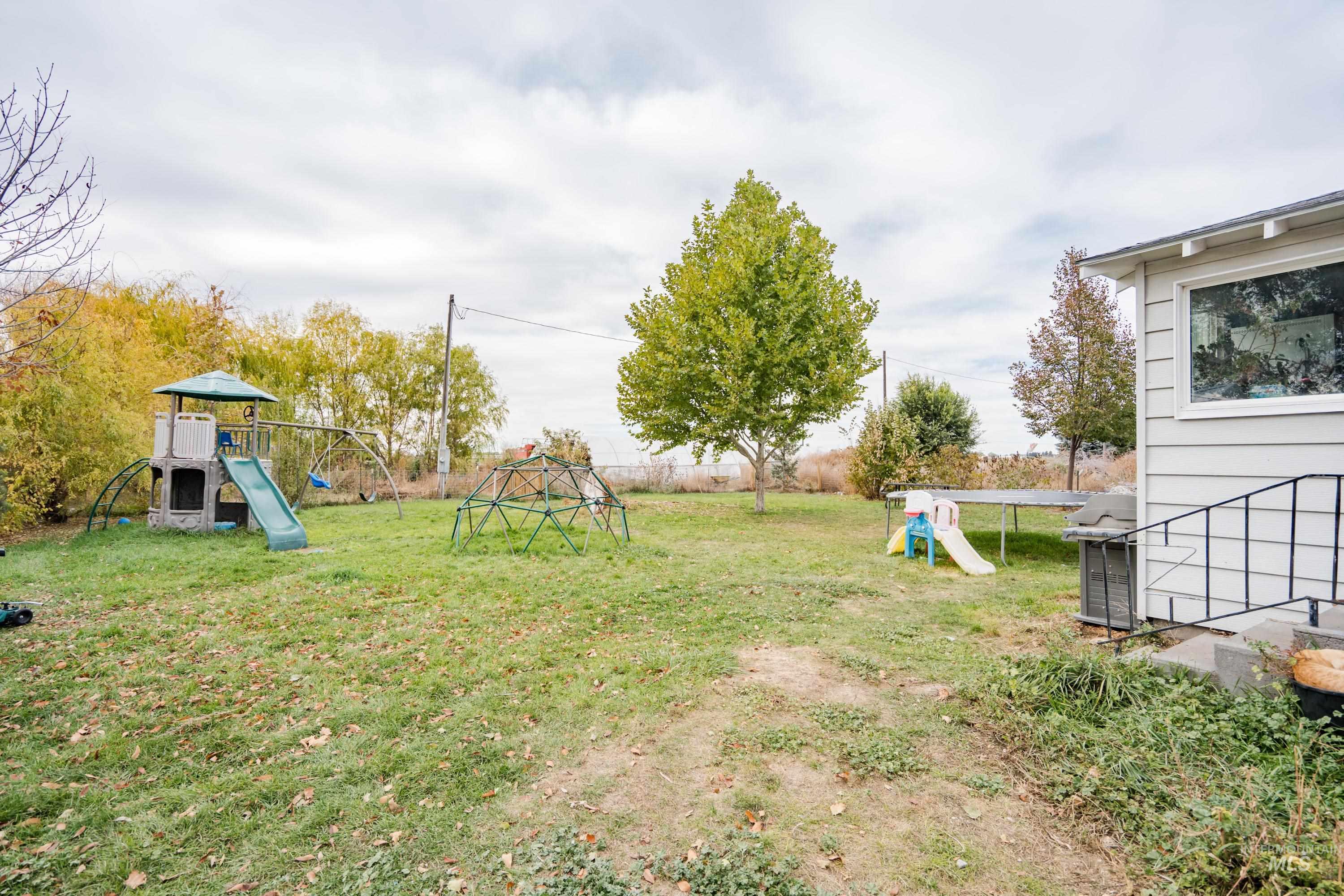 View of grassy yard with a playground and a trampoline