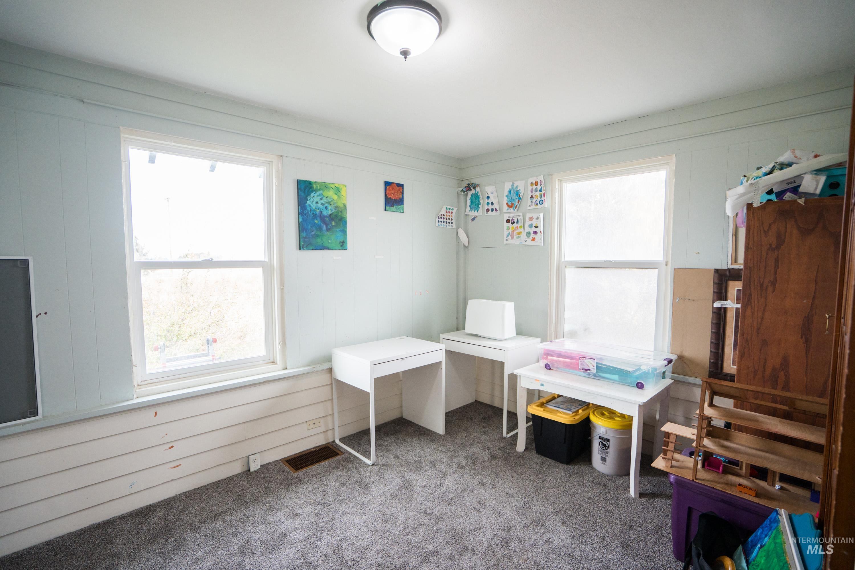 Carpeted bedroom featuring wood walls and multiple windows