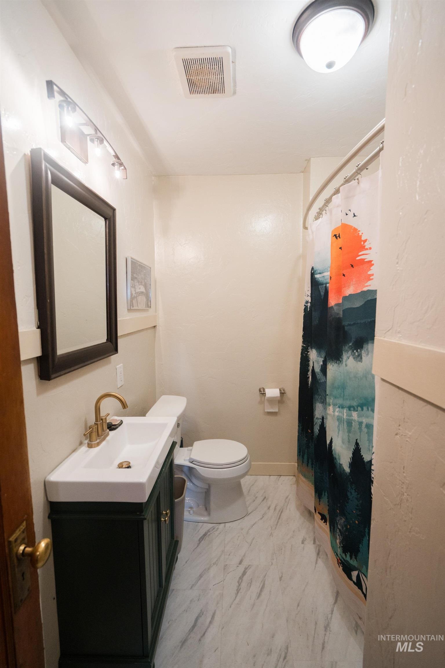 Bathroom featuring a shower with shower curtain, vanity, and light marble finish floors