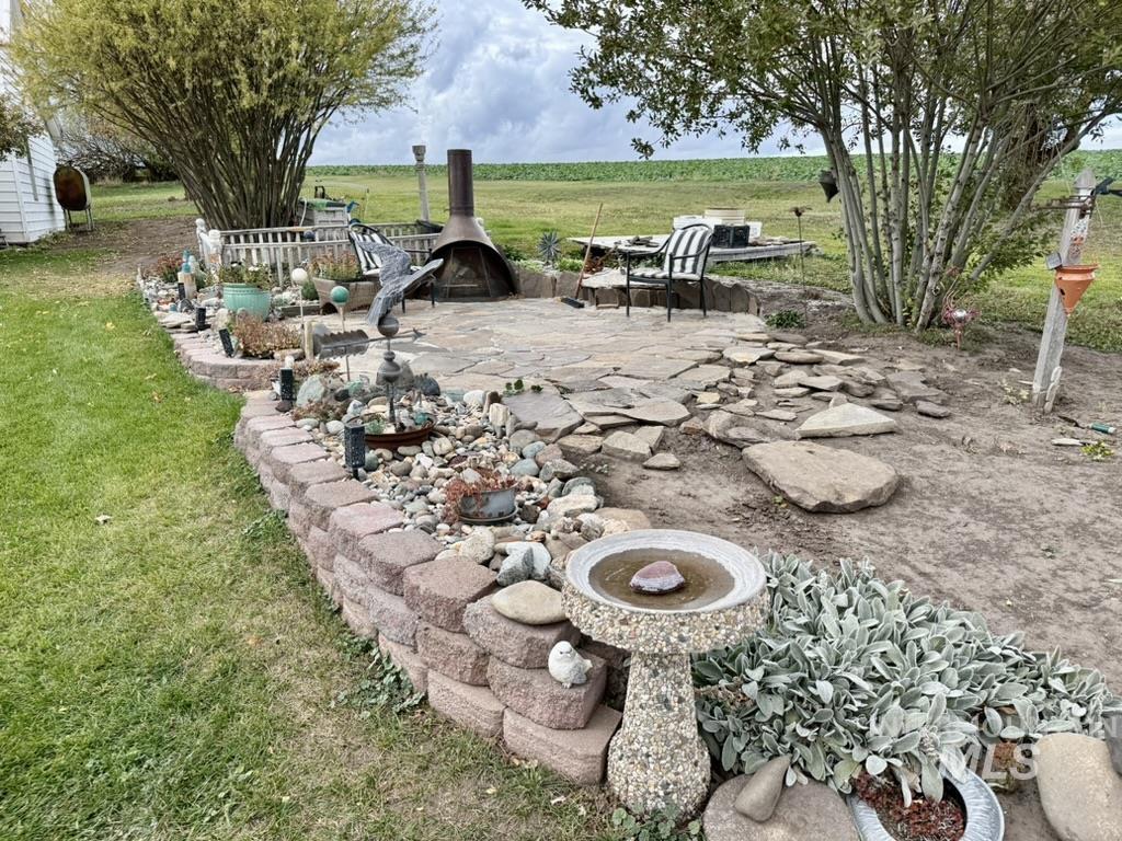View of green lawn with a patio and a rural view