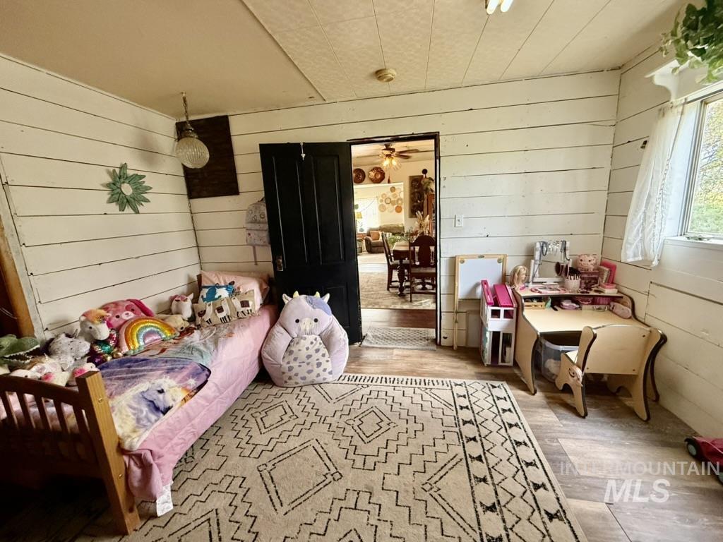 Bedroom featuring wood finished floors and wood walls