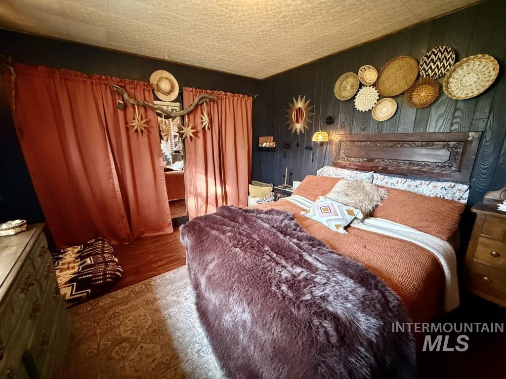 Bedroom with wood finished floors, wooden walls, and an ornate ceiling