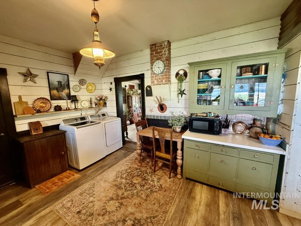Kitchen featuring green cabinets, wooden walls, dark wood-style floors, pendant lighting, and light countertops