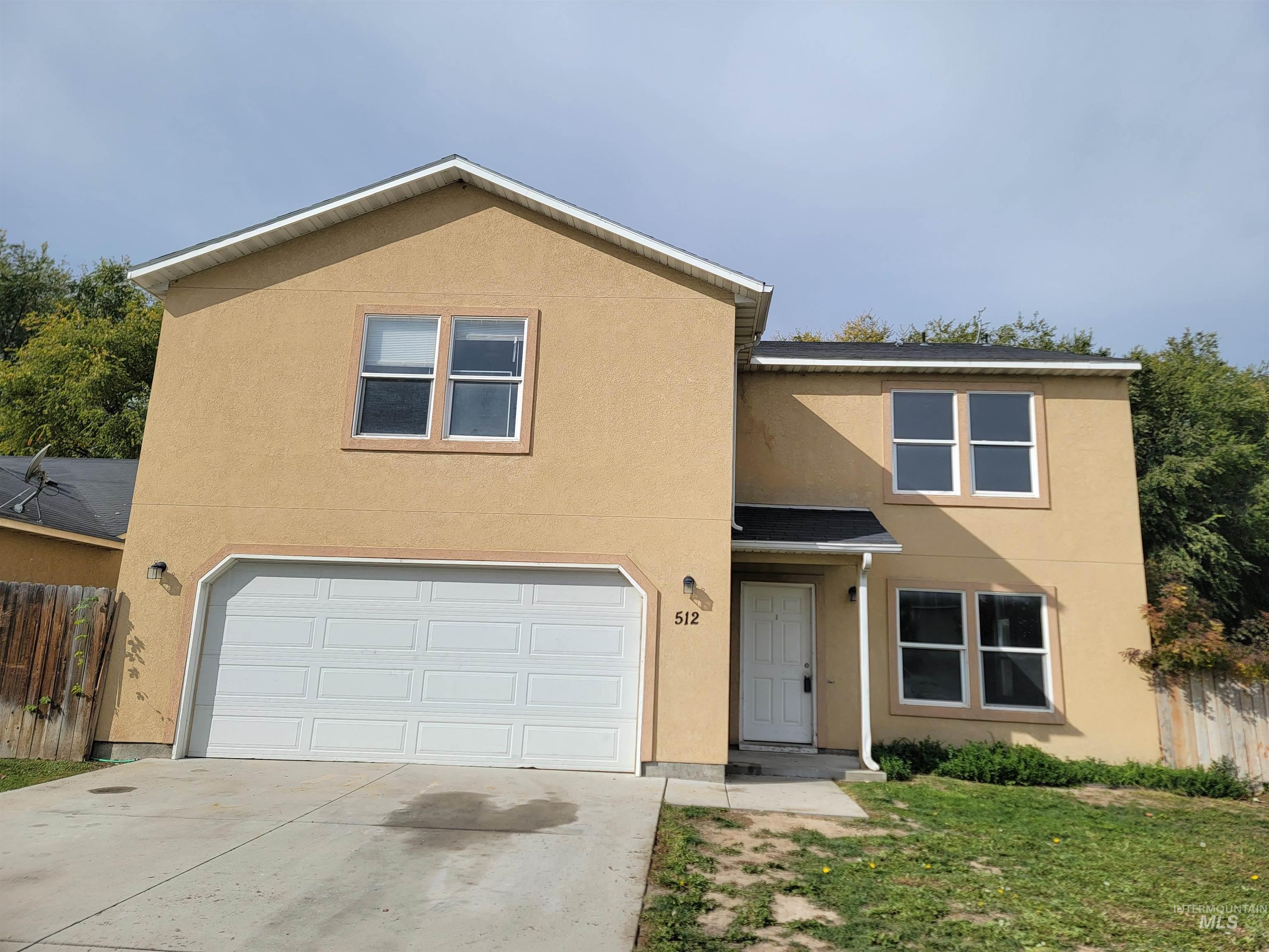 Traditional-style home featuring an attached garage, stucco siding, and concrete driveway