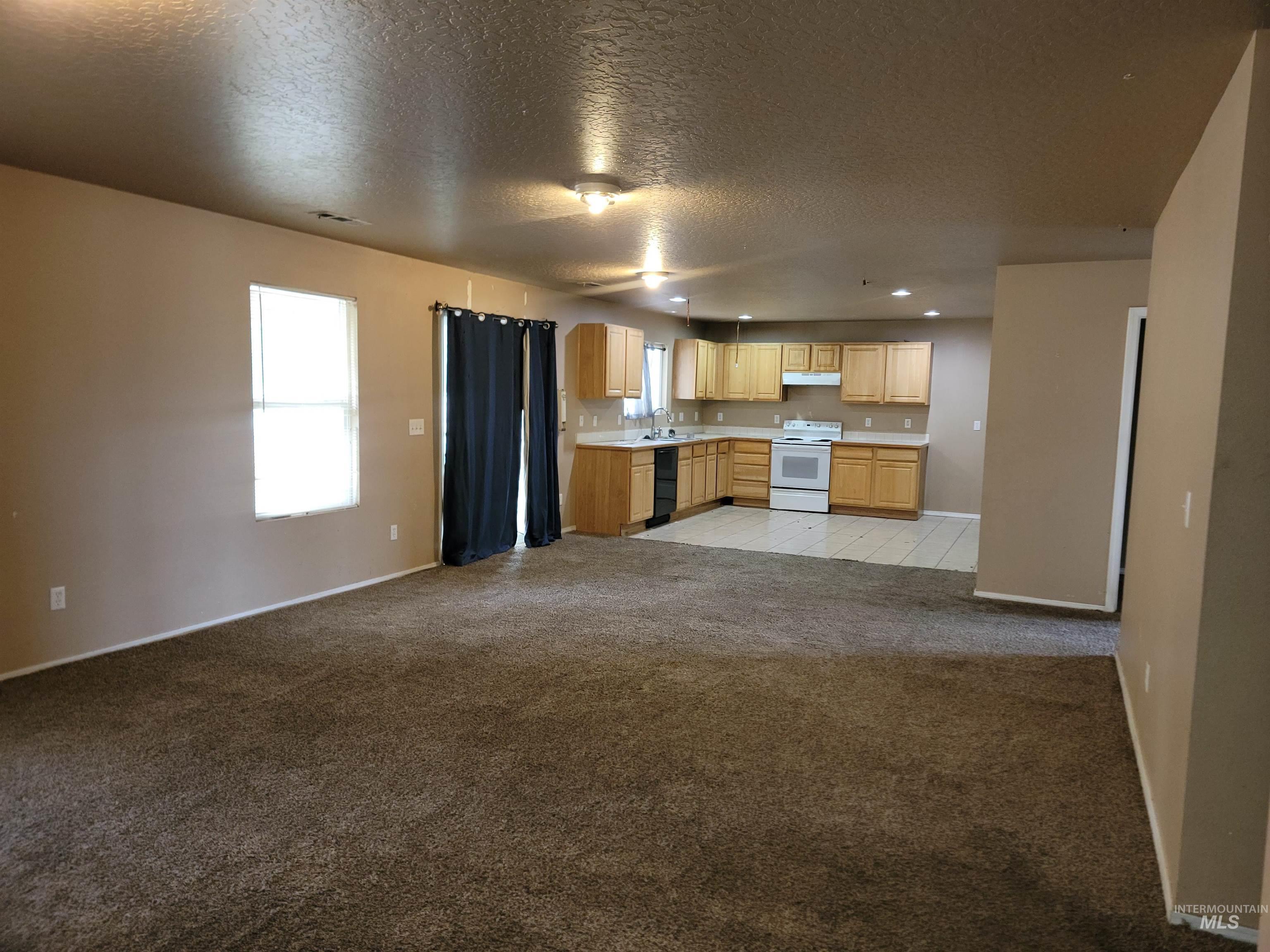 Kitchen with light carpet, light brown cabinetry, white range with electric cooktop, open floor plan, and plenty of natural light
