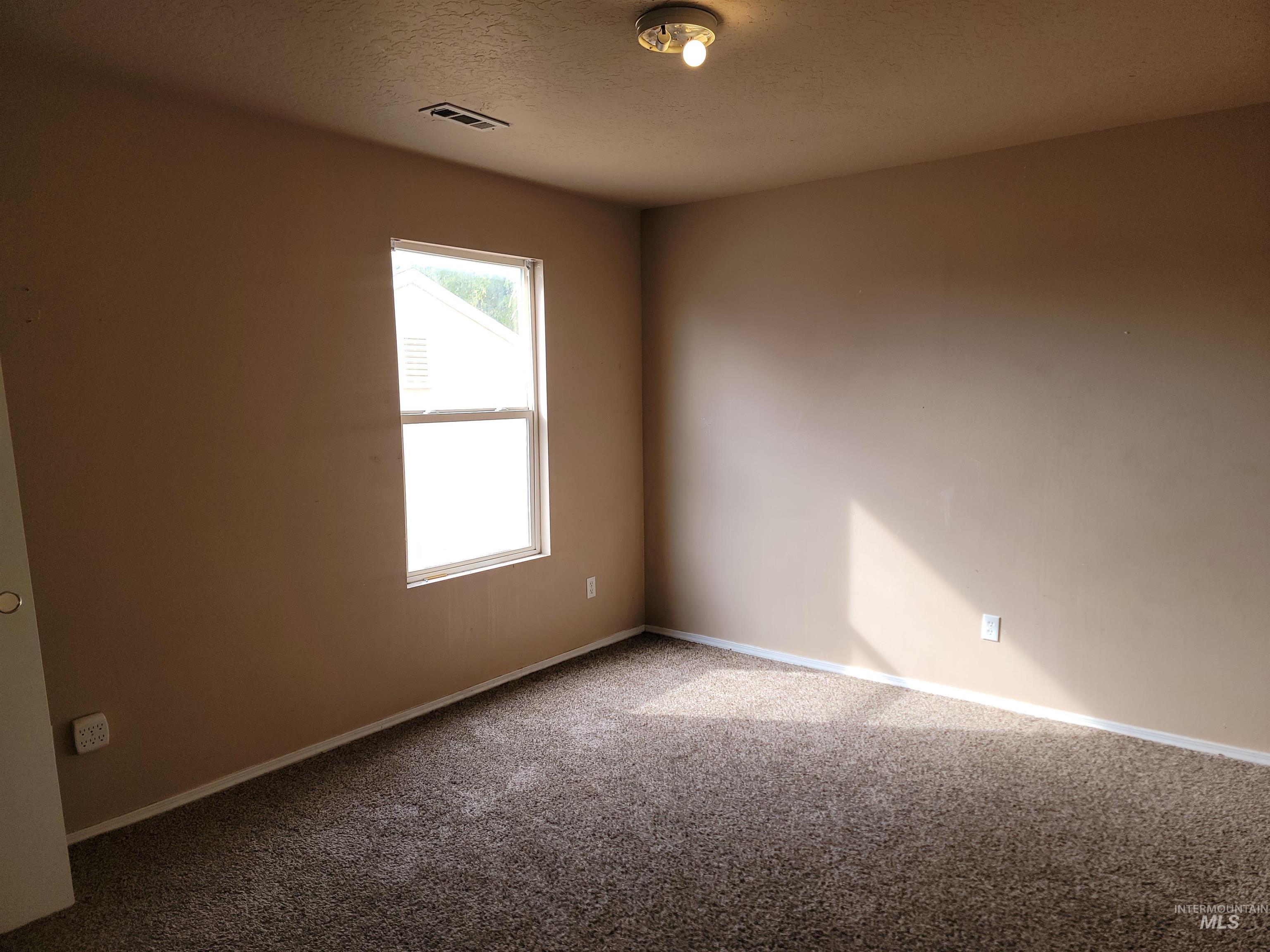Carpeted empty room with baseboards and a textured ceiling