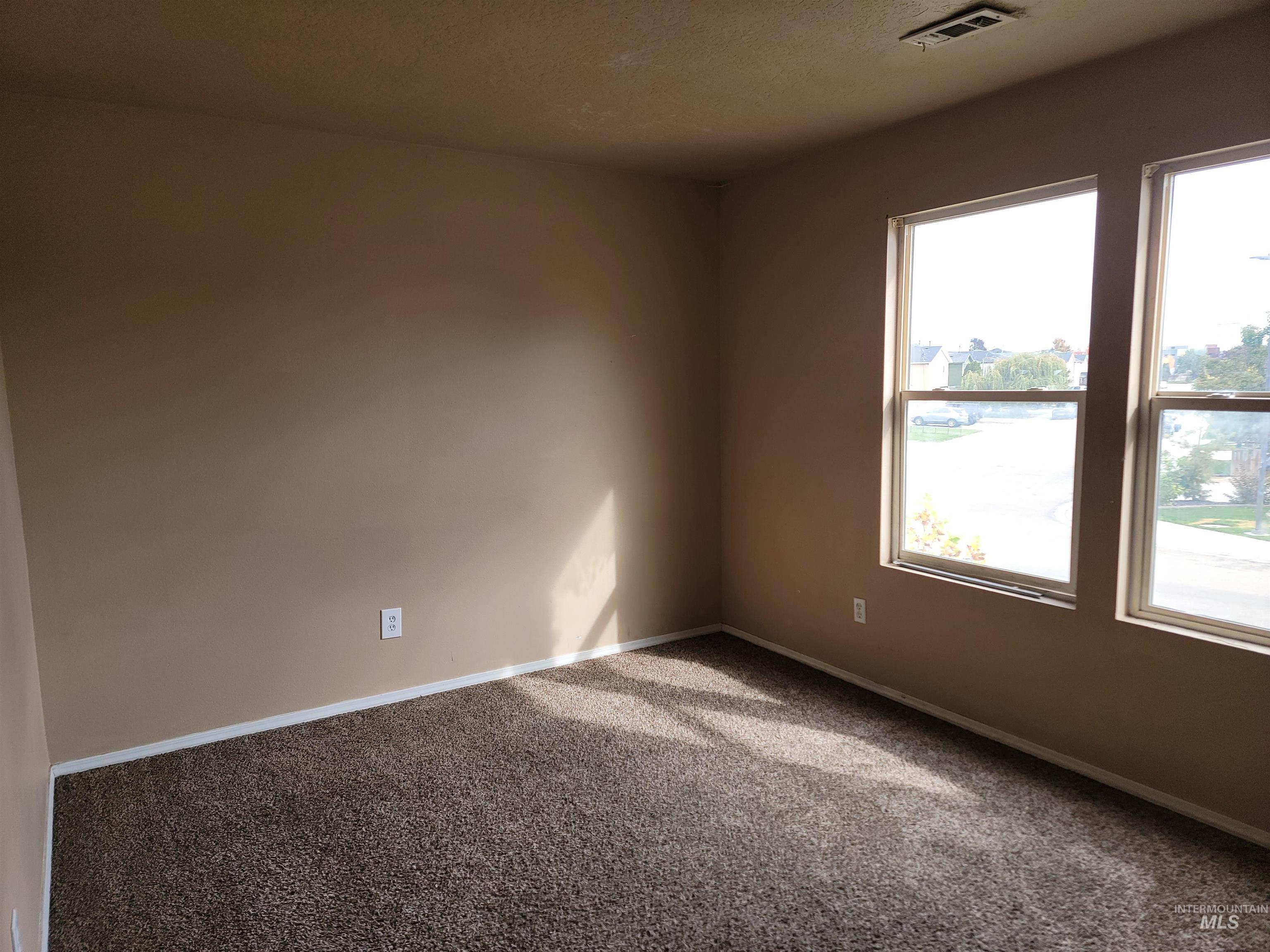 Carpeted spare room featuring baseboards and a textured ceiling