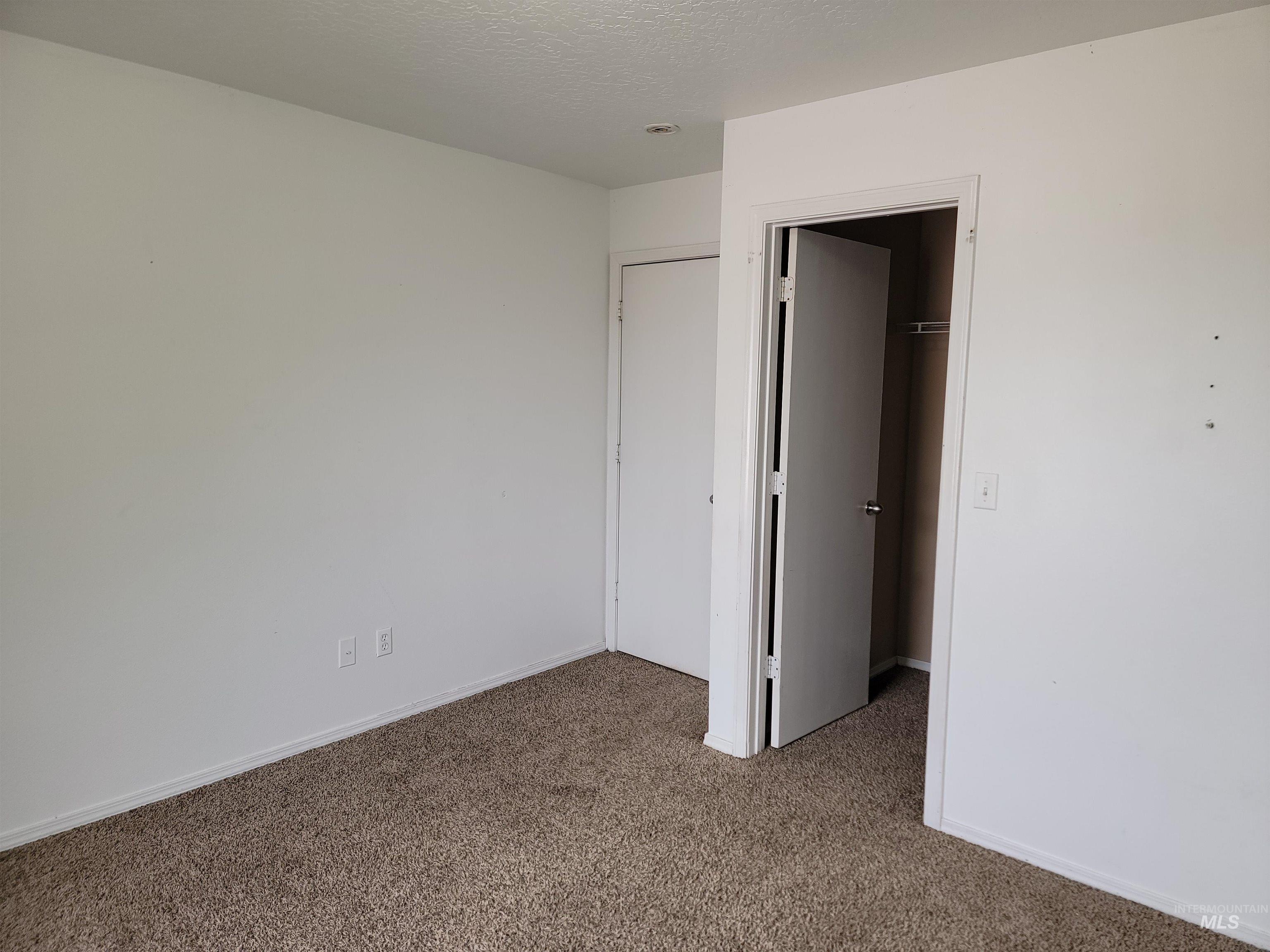 Unfurnished bedroom with carpet floors, a textured ceiling, and a spacious closet