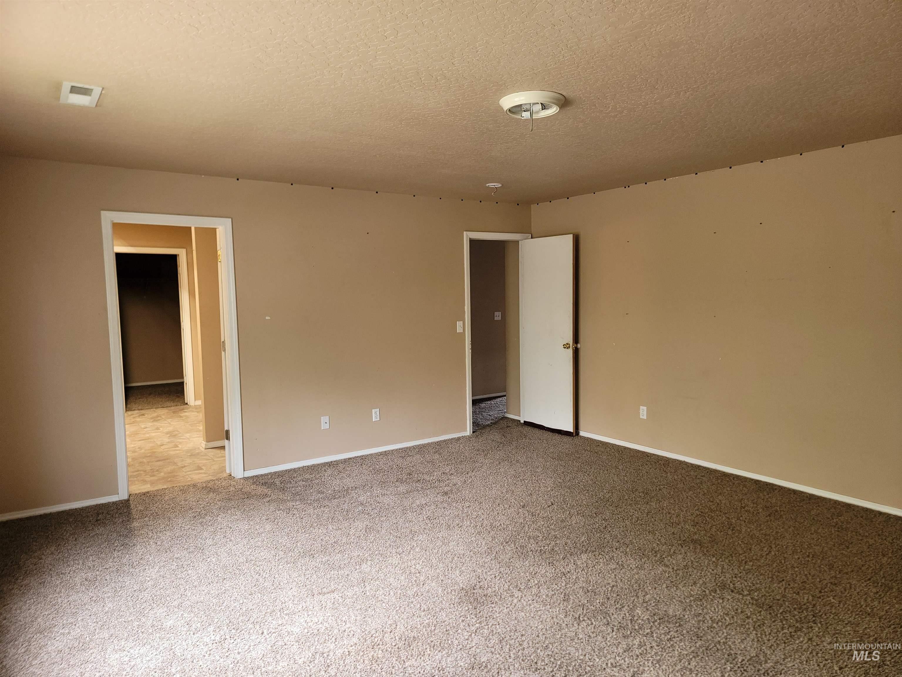 Unfurnished bedroom featuring a textured ceiling and light carpet