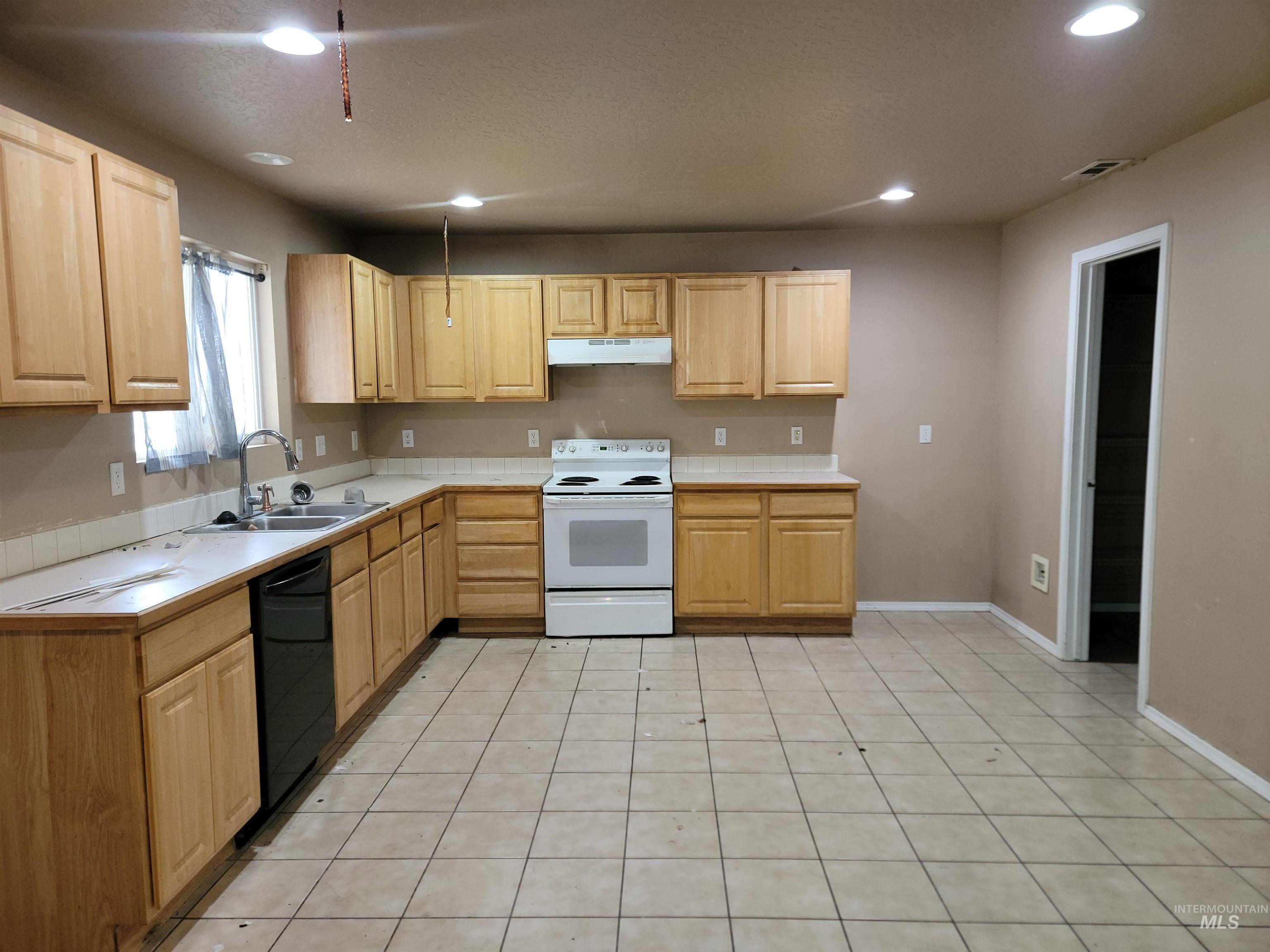 Kitchen featuring electric stove, light tile patterned flooring, tile counters, dishwasher, and recessed lighting
