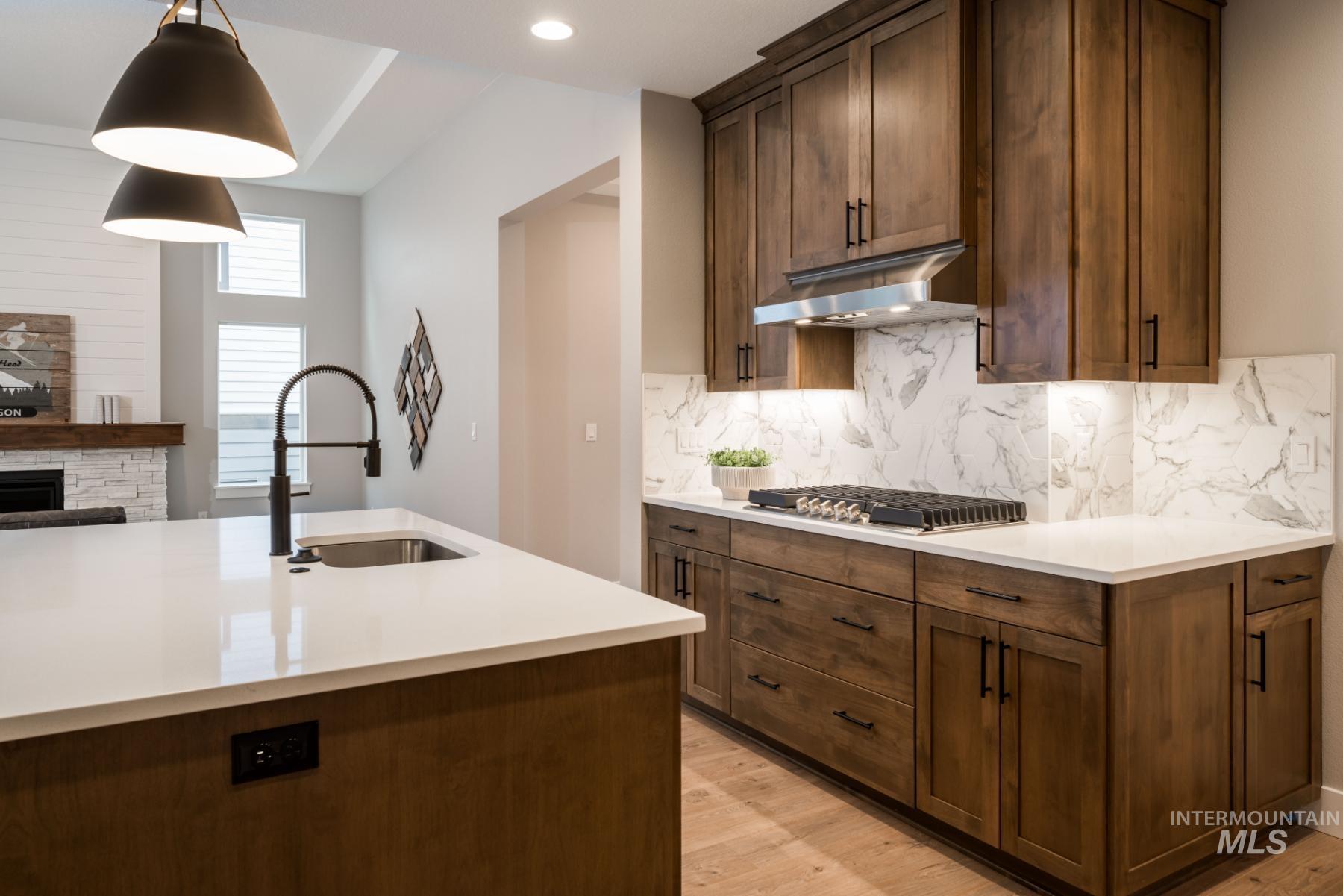 Kitchen with light wood-style flooring, light countertops, and ventilation hood