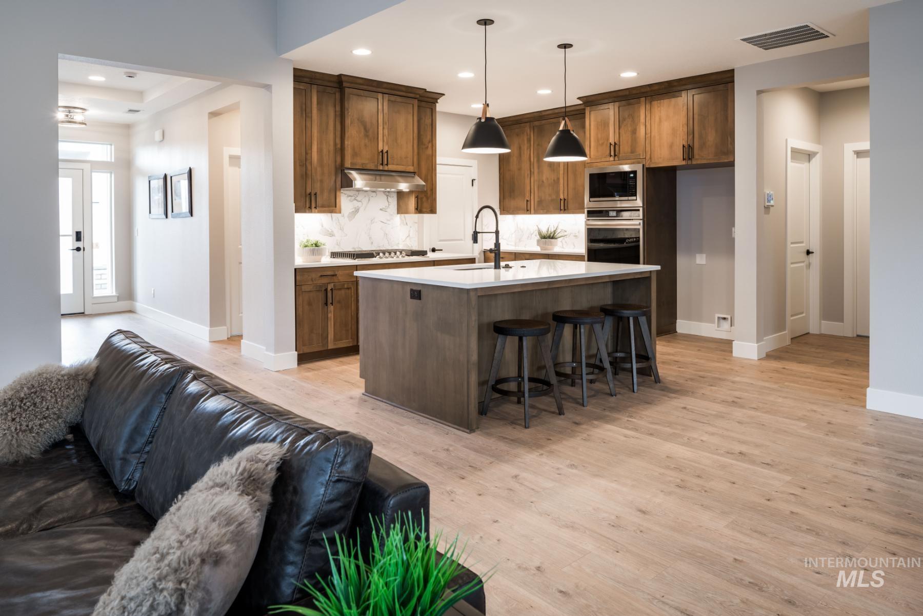 Kitchen with open floor plan, backsplash, light wood-style floors, a kitchen bar, and light countertops