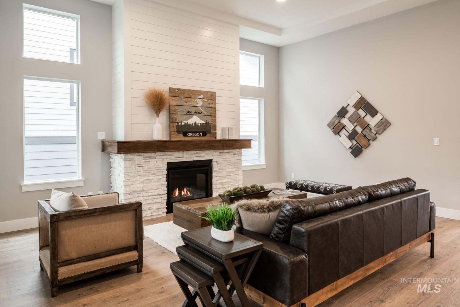 Living area featuring wood finished floors, a stone fireplace, and a high ceiling