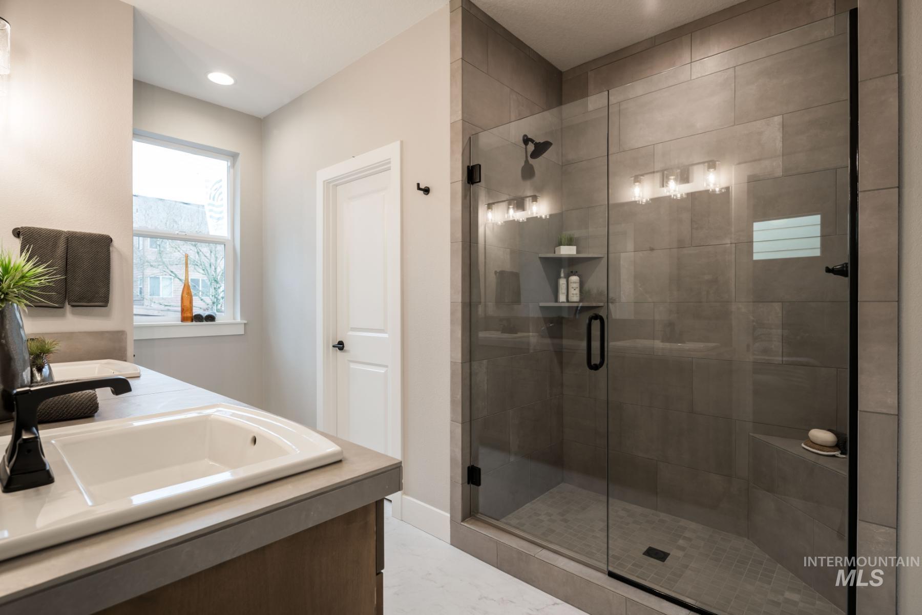 Bathroom featuring a shower stall, double vanity, recessed lighting, and marble finish floors