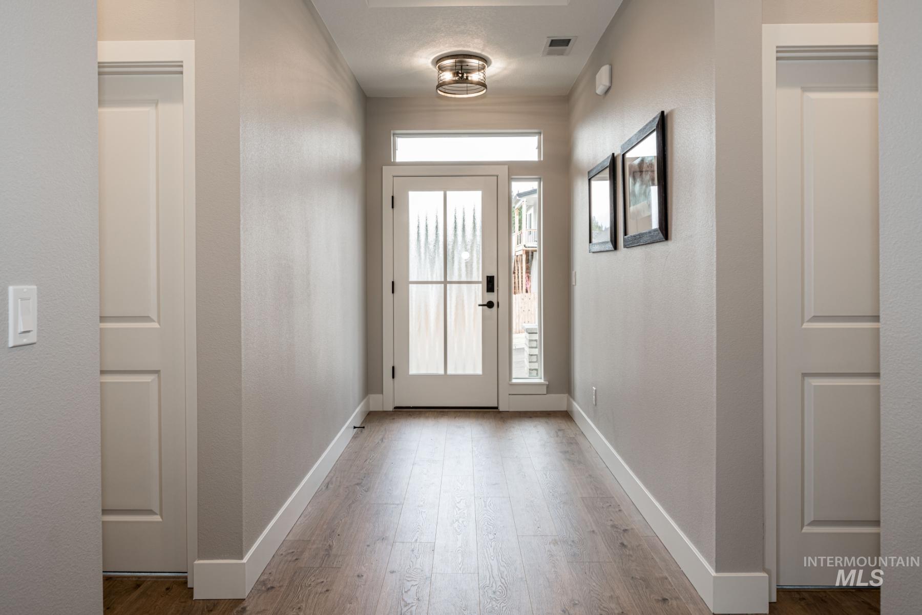 Doorway with wood finished floors and a textured wall