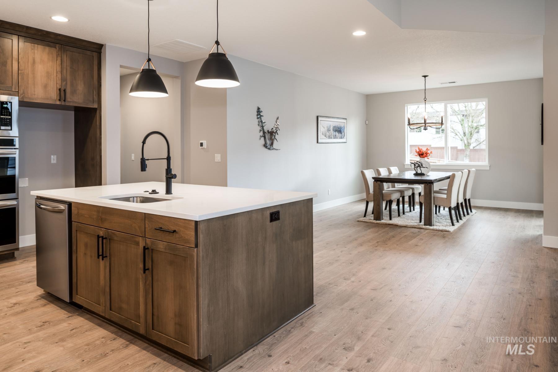 Kitchen featuring recessed lighting, light wood-style flooring, pendant lighting, light countertops, and appliances with stainless steel finishes