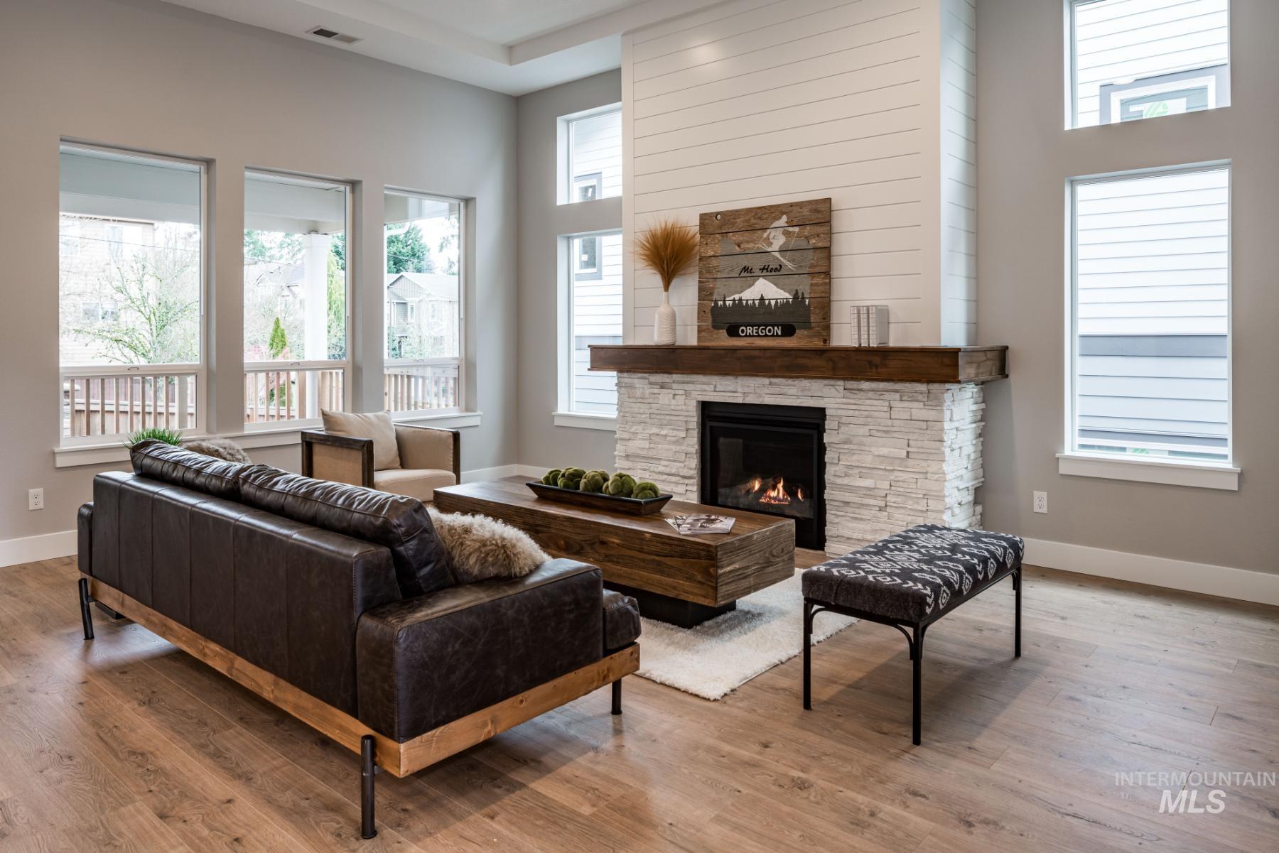 Living area with a fireplace, wood finished floors, and a high ceiling