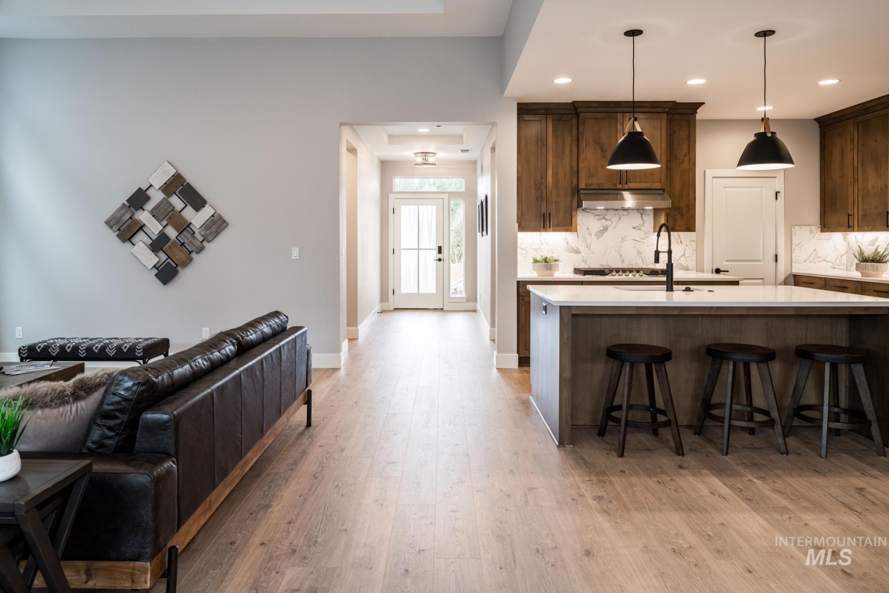 Kitchen with light countertops, decorative backsplash, light wood finished floors, a breakfast bar area, and open floor plan