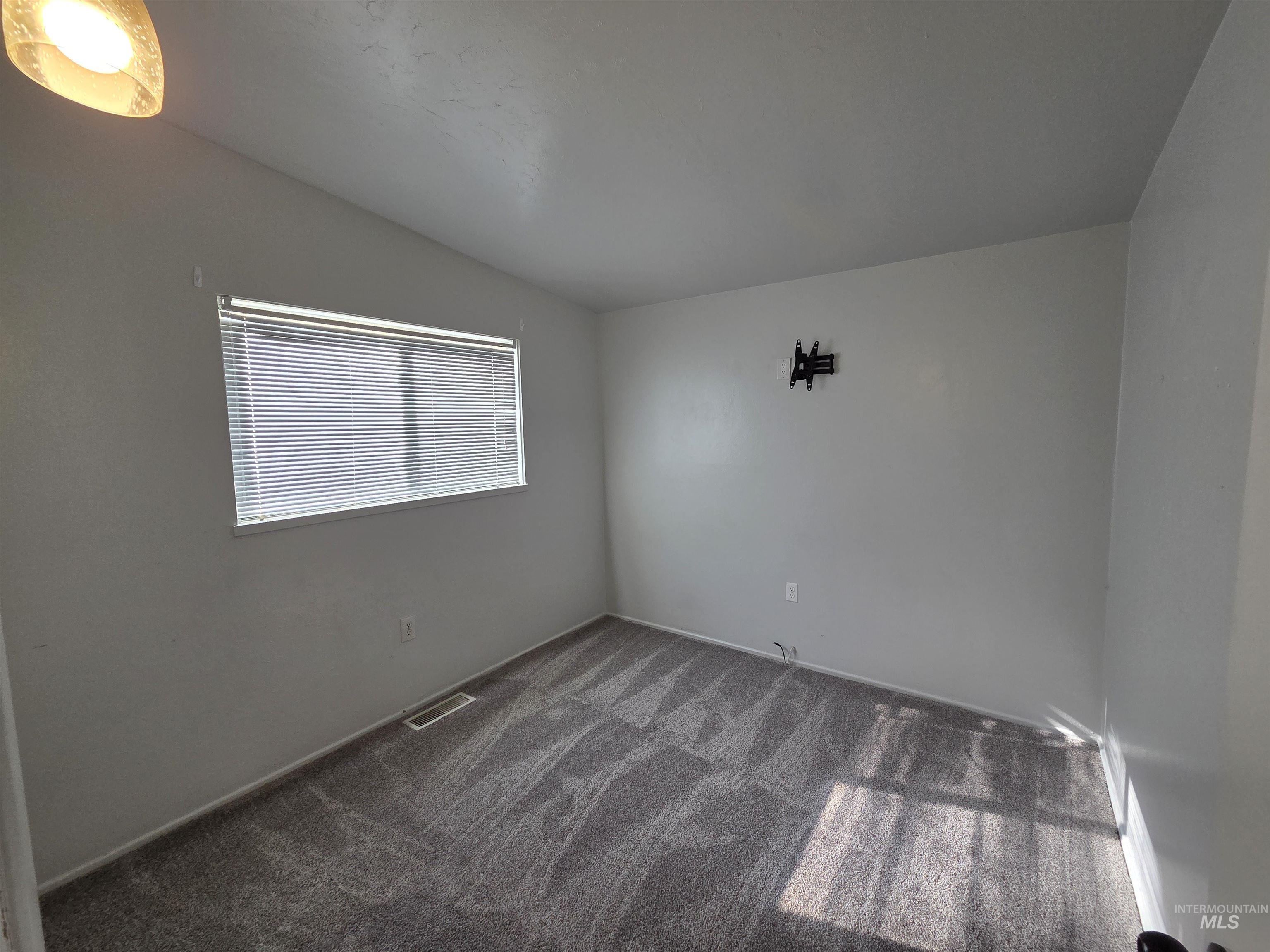 Empty room with dark colored carpet and baseboards