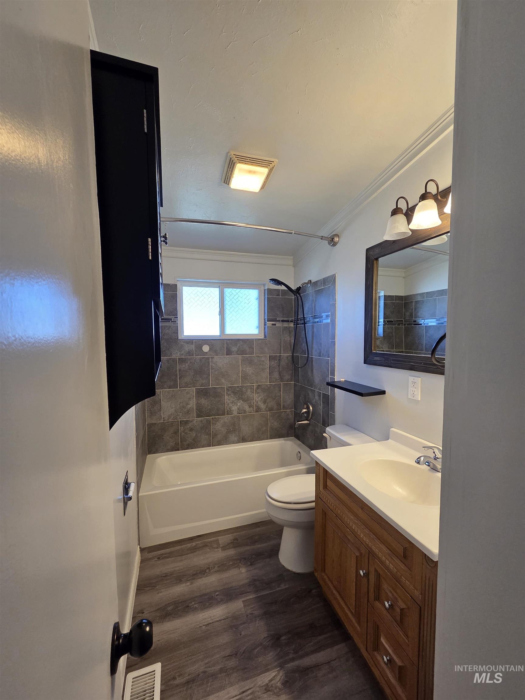 Full bathroom featuring shower / tub combination, vanity, dark wood finished floors, and ornamental molding