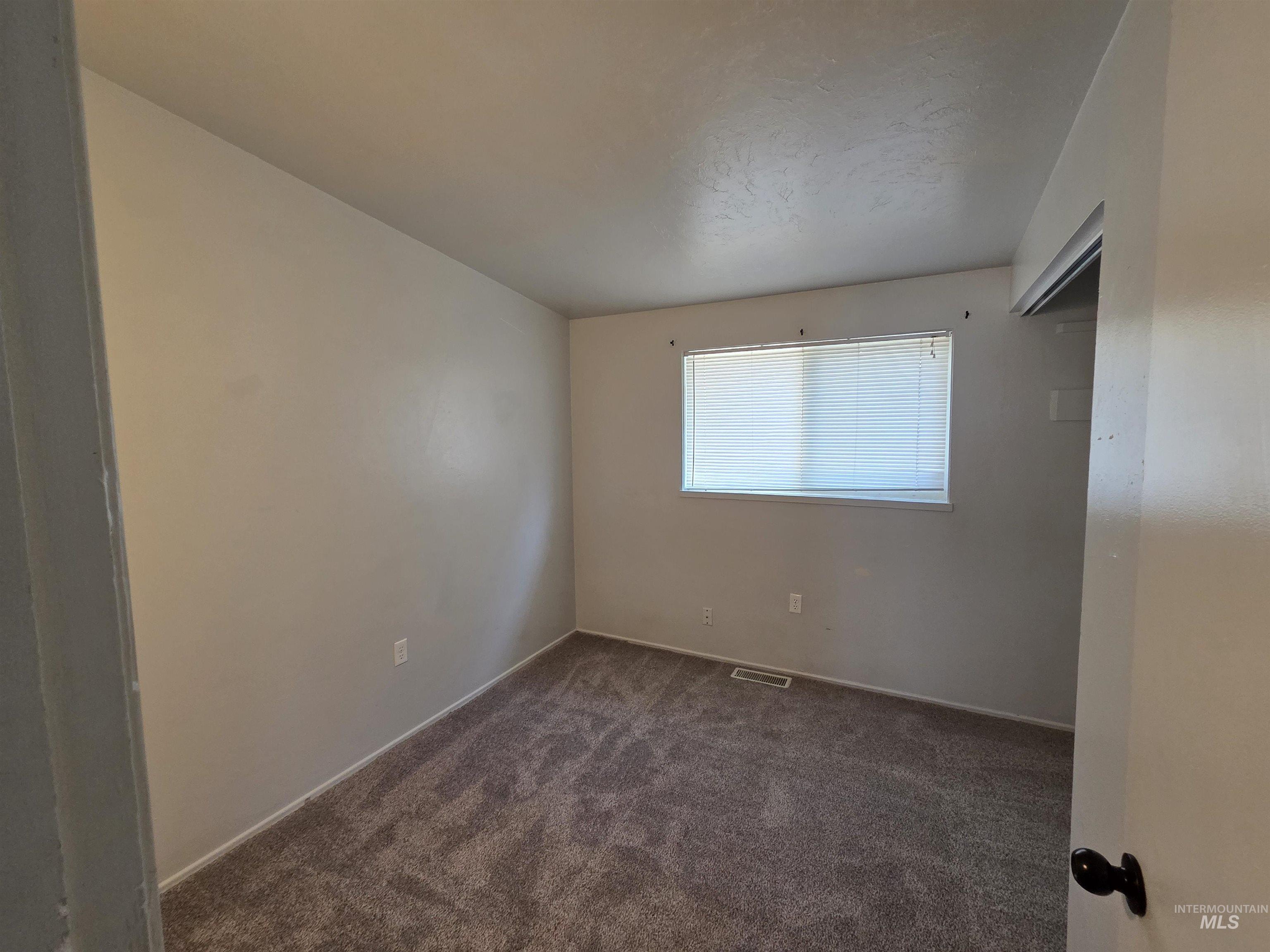 Unfurnished bedroom with dark carpet and a closet