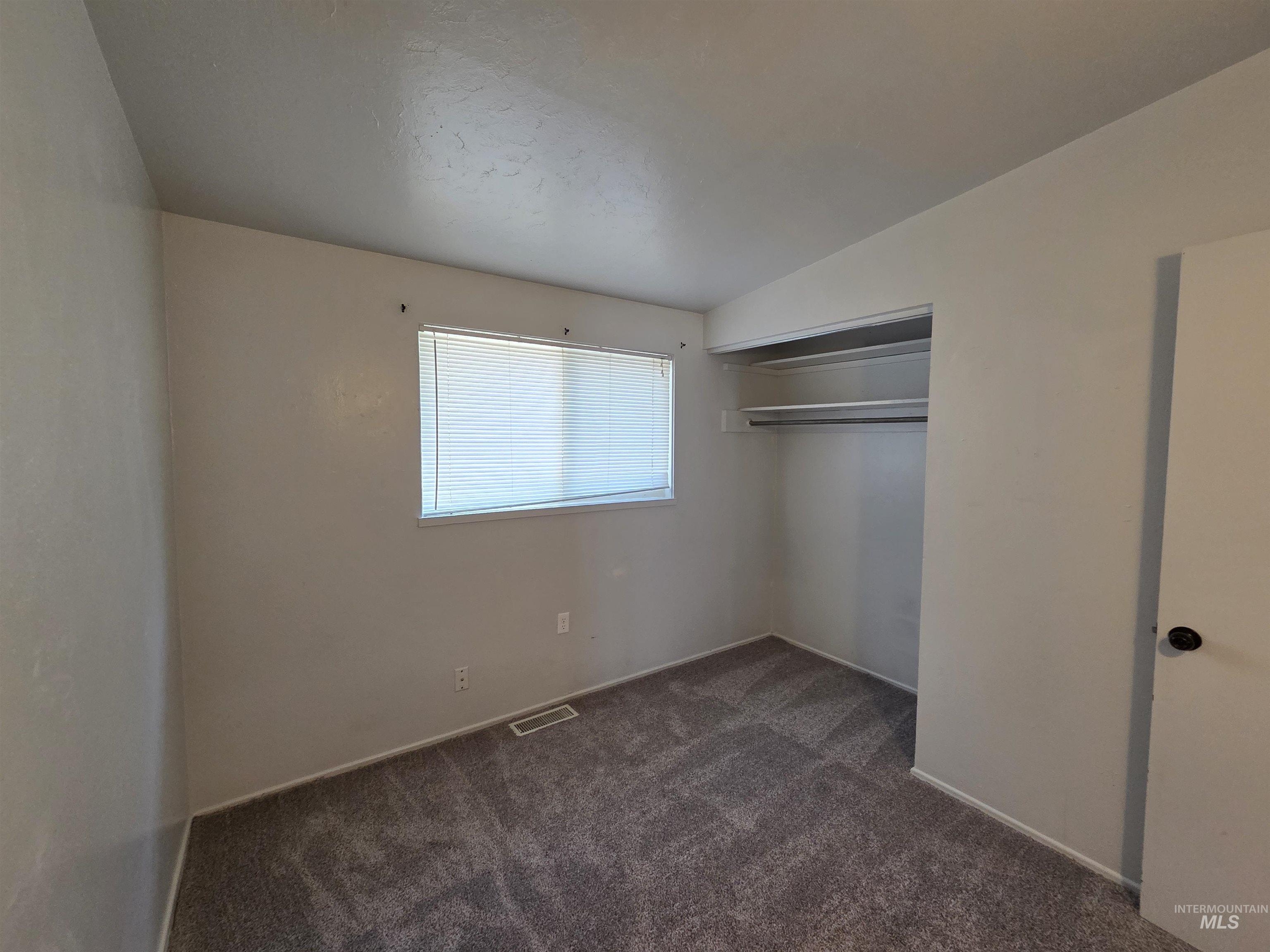 Unfurnished bedroom with dark carpet and a closet