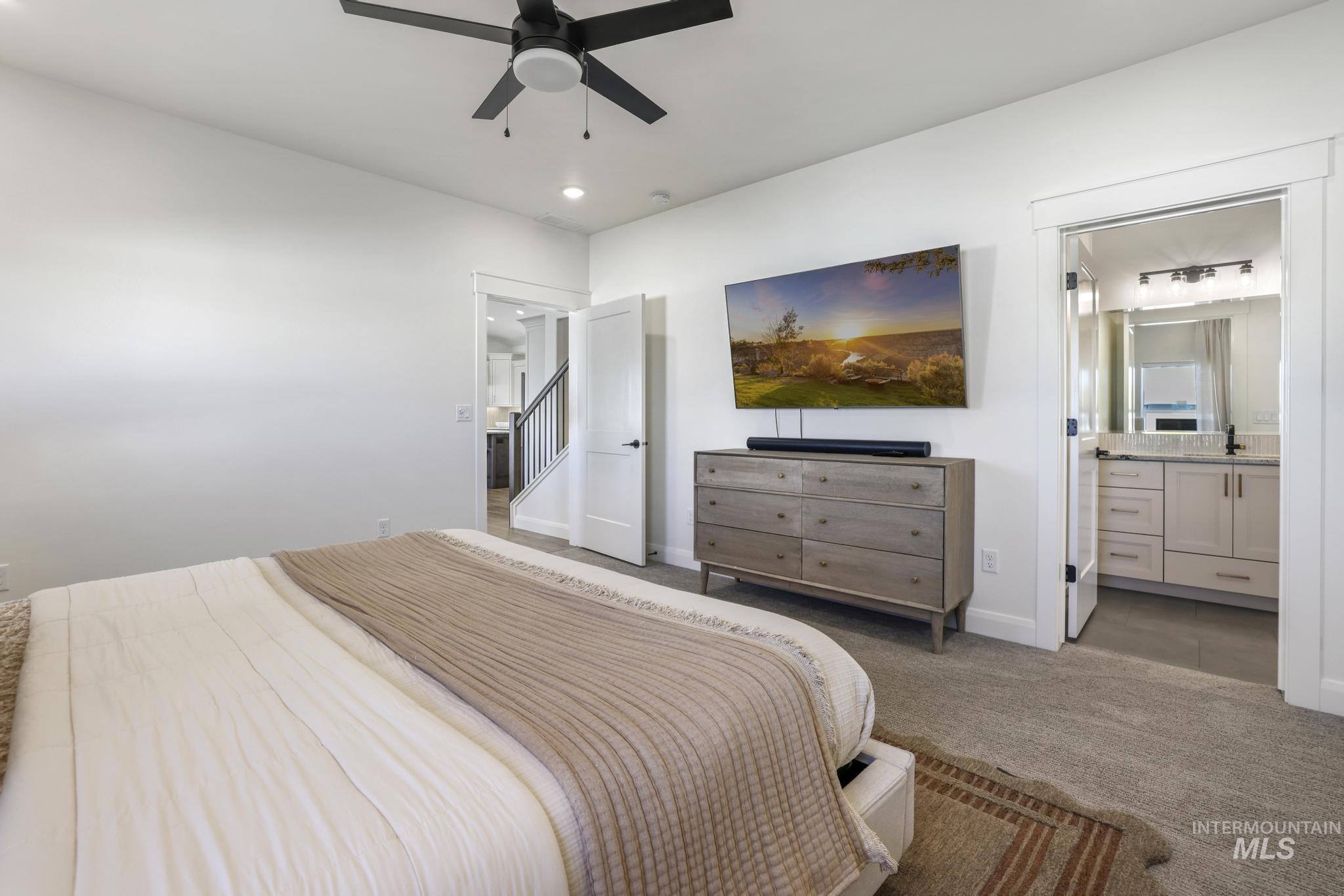 Carpeted bedroom with a ceiling fan, ensuite bathroom, and recessed lighting