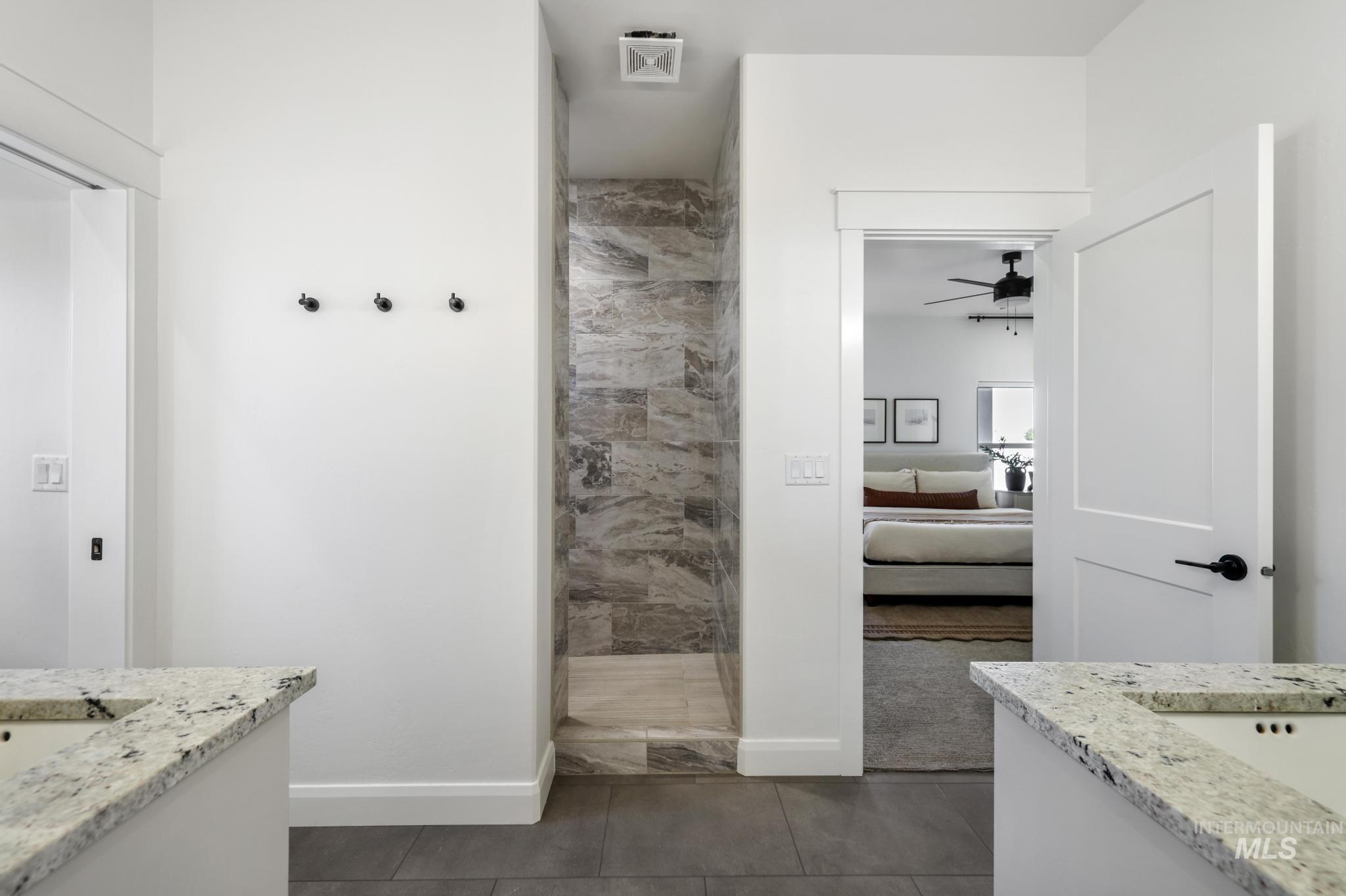 Full bath with vanity, dark tile patterned flooring, a walk in shower, and ensuite bath